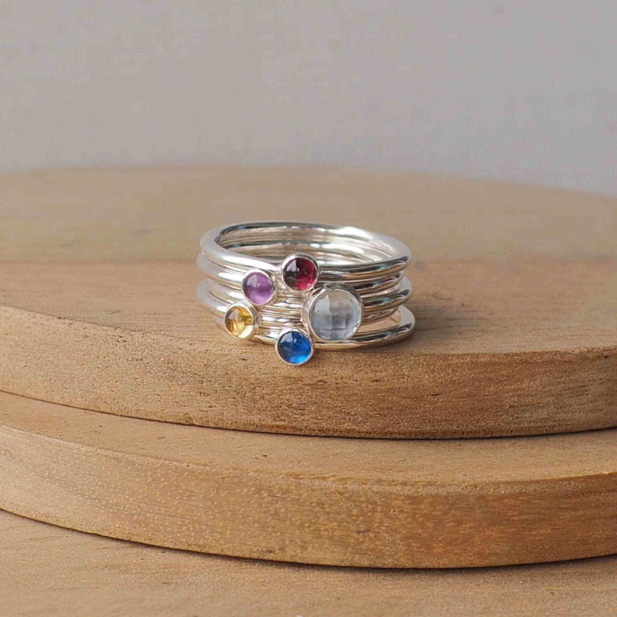 Five Ring Set with Blue Topaz, Amethyst, Lab Sapphire and Citrine and Garnet to mark March, February, September, January and November Birthdays. The five rings are made with Sterling Silver and a 5mm blue round cabochon, with three further rings with 3mm round gems in a yellow citrine, purple amethyst, red garnet and a bright blue lab sapphire. Handmade in Scotland by maram jewellery