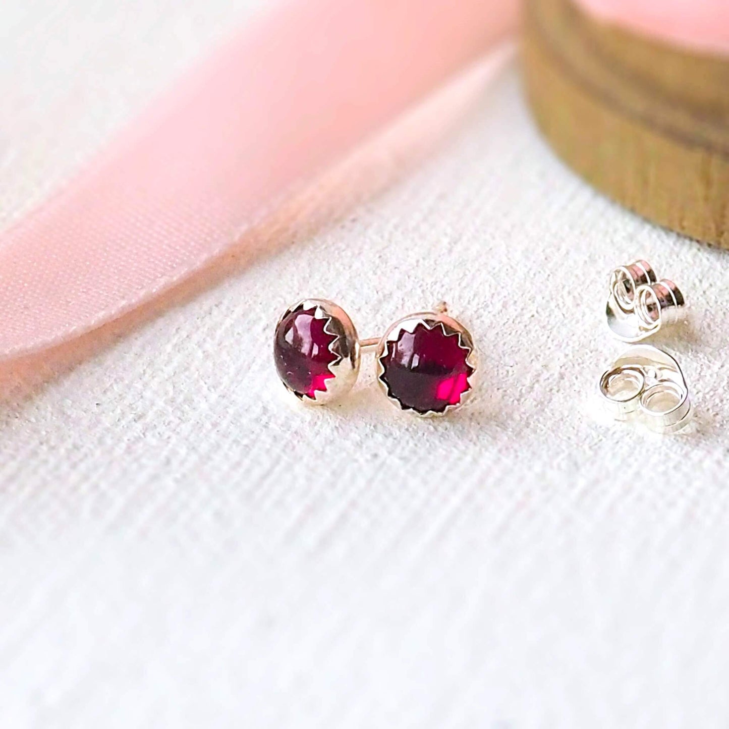 Beautifully simple modern gemstone earrings with a raspberry red round garnet set by hand into a modern minimalist sterling silver surround. The earrings are 5mm in size, round and come with butterfly backs. These stud earrings are handcrafted by a small business in Scotland UK by designer jeweller Maram Jewellery