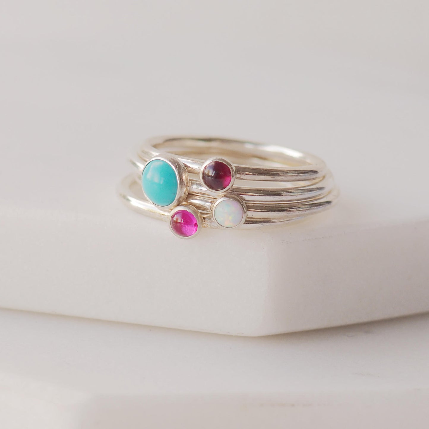 Four ring birthstone set with a large Turquoise, smaller garnet, Lab Opal and Lab Ruby. Handmade by maram jewellery in Scotland UK