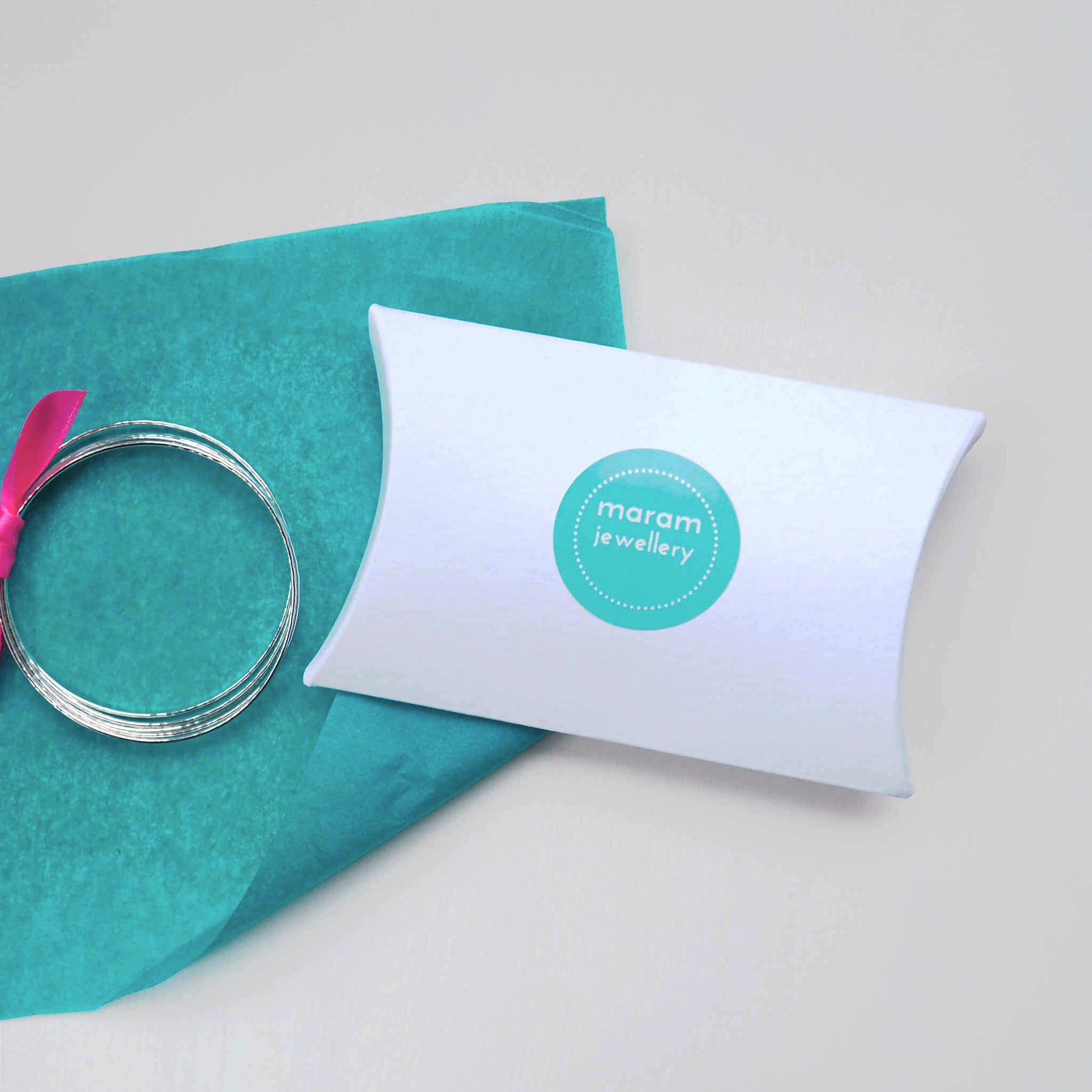 maram jewellery simple pillow box packing, a white luxury card pillow box with maram jewellery logo in turquoise with matching tissue