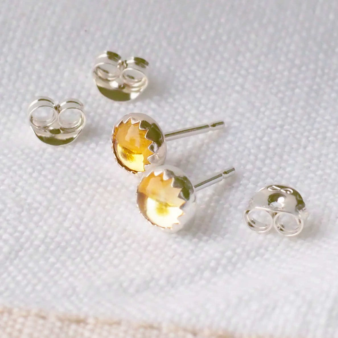 Simple Modern Gemstone stud earrings in sterling silver and round citrine. The earrings measure 5mm in size and are very simply set with a unusual wavy edge. Handmade in Scotland by a small independent jeweller, maram jewellery