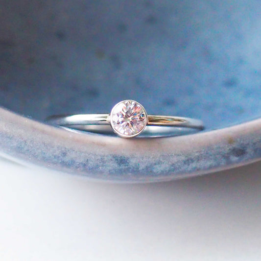 Silver and imitation diamond cubic zirconia ring in sterling silver on a blue pottery style background. a handmade ring by maram jewellery handcrafted in Scotland