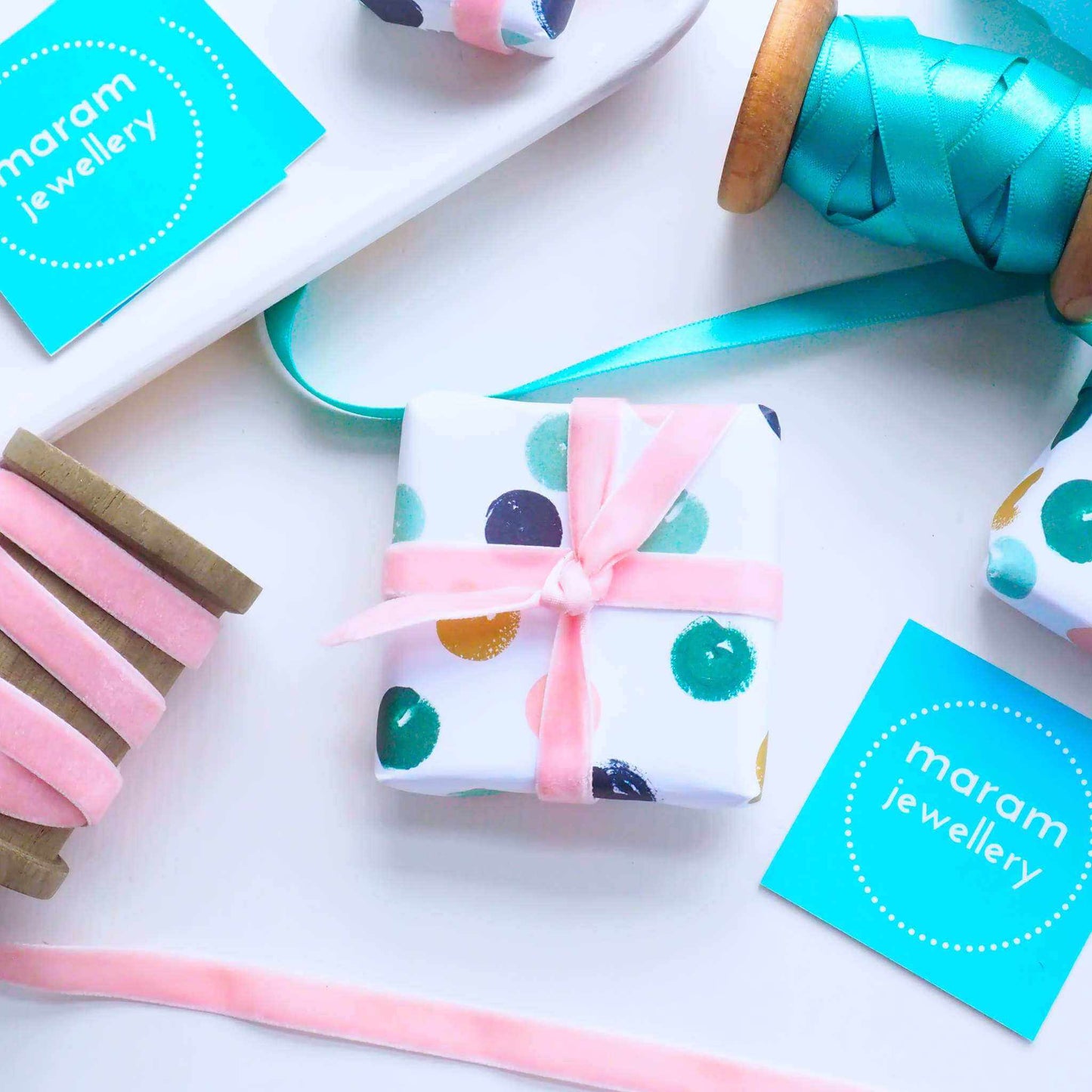 Ring box wrapped with luxury white gift wrap with coloured dots in green, gold and pink, tied neatly with a ribbon. Gift wrap option for maram jewellery