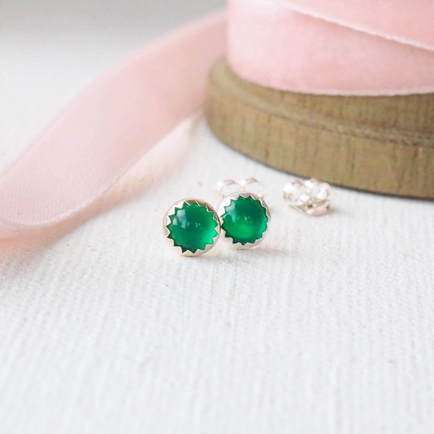 Simple round gemstone earrings in bright green agate, with a simple silver surround. minimalist in style, suitable for everyday earrings, pictures on a white textured background with gently pink ribbon