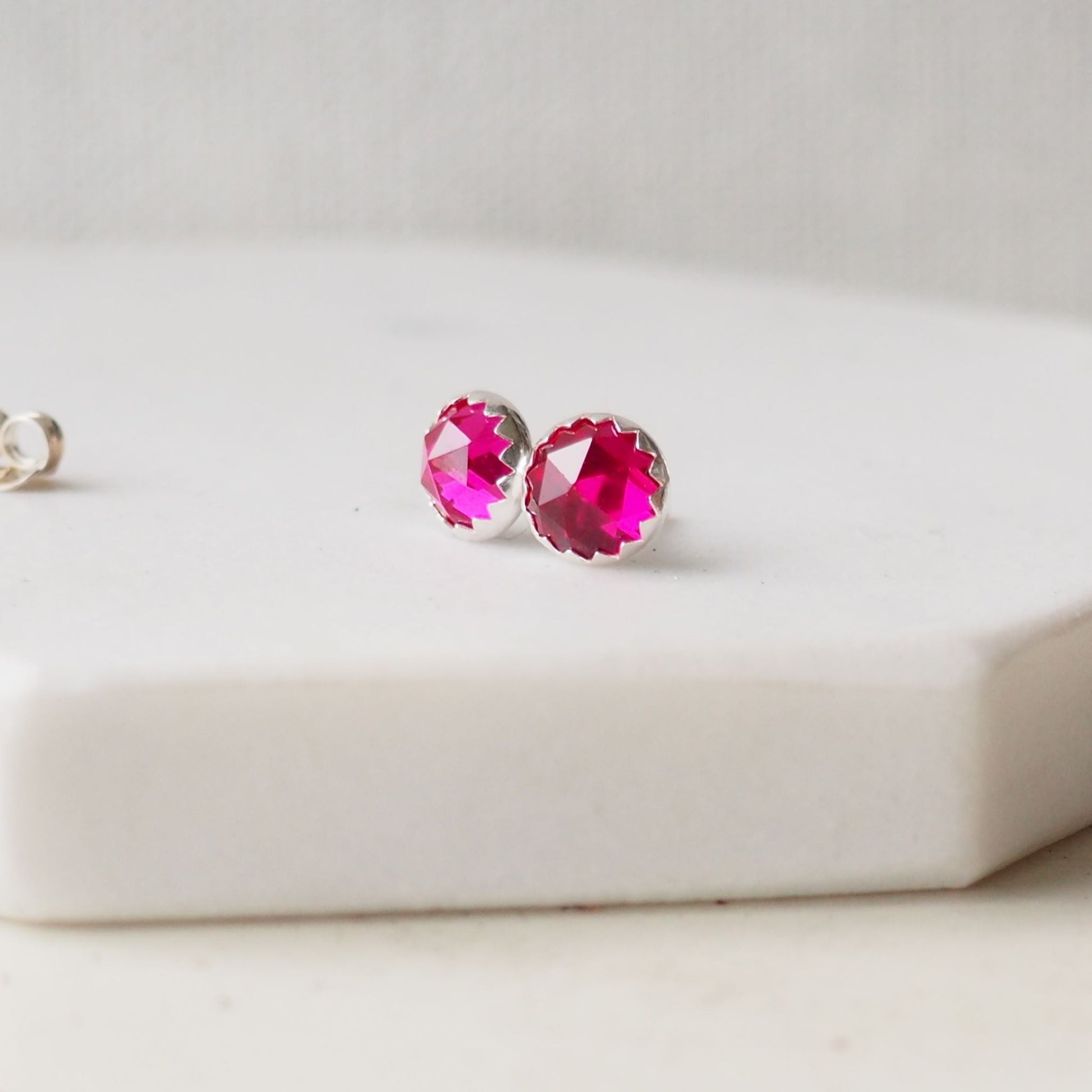 Lab Ruby Gemstone stud earrings with a bright hot pink artificial gemstone, round and faceted 6m in size. Set onto Sterling Silver settings. Birthstone for July Handmade in Scotland UK by maram jewellery