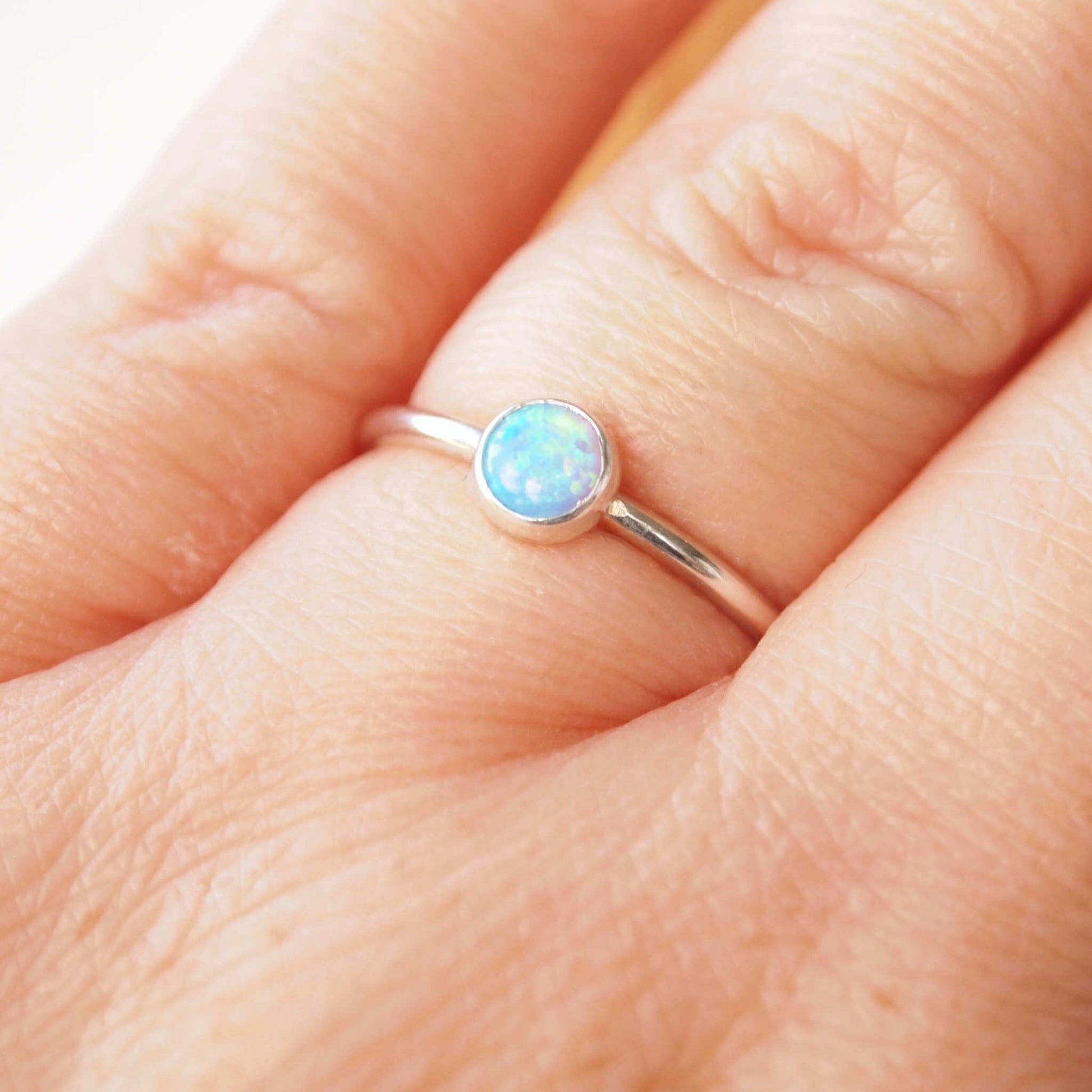 Simple style Lab Opal and Sterling Silver single Solitaire Ring with Lab Opal. Opal is Birthstone for October. THe round 5mm gem is a blue opal with lots of iridescence. Handmade by Maram Jewellery in Scotland