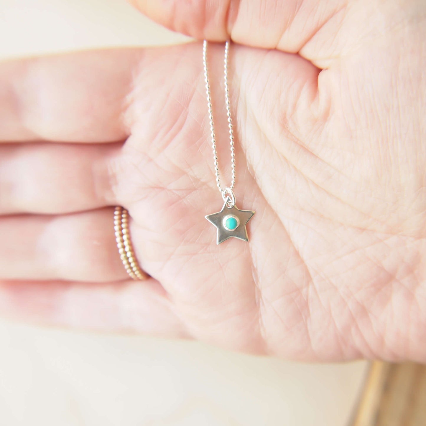 December Birthstone Charm Necklace in the shape of a star with a round 3mm Turquoise cabochon centre. The star measures 12mm in size so is small enough for children as well as adults and is available in a range of other birthstones too. It is Sterling Silver and comes with a choice of chain design and length. Handmade in Scotland by Maram Jewellery