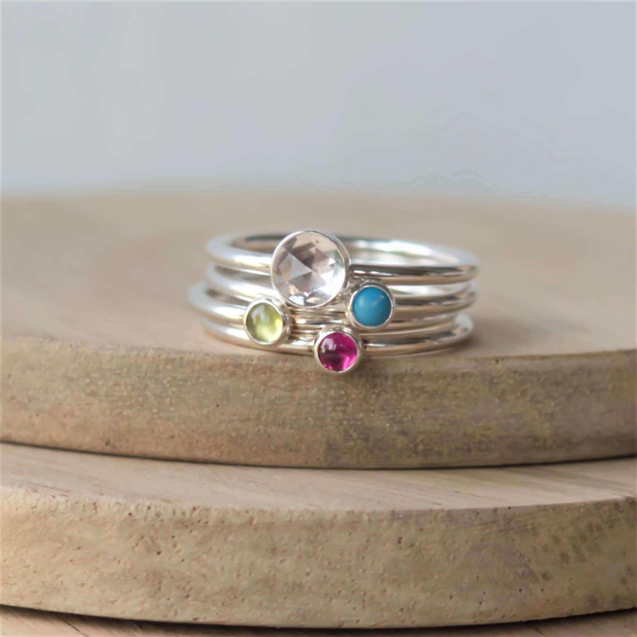 Four ring set of silver rings with different sized gemstones. Includes a 5mm facet clear topaz, turquoise, peridot and pink lab ruby all 3mm in size. Handmade by maram jewellery in Edinburgh