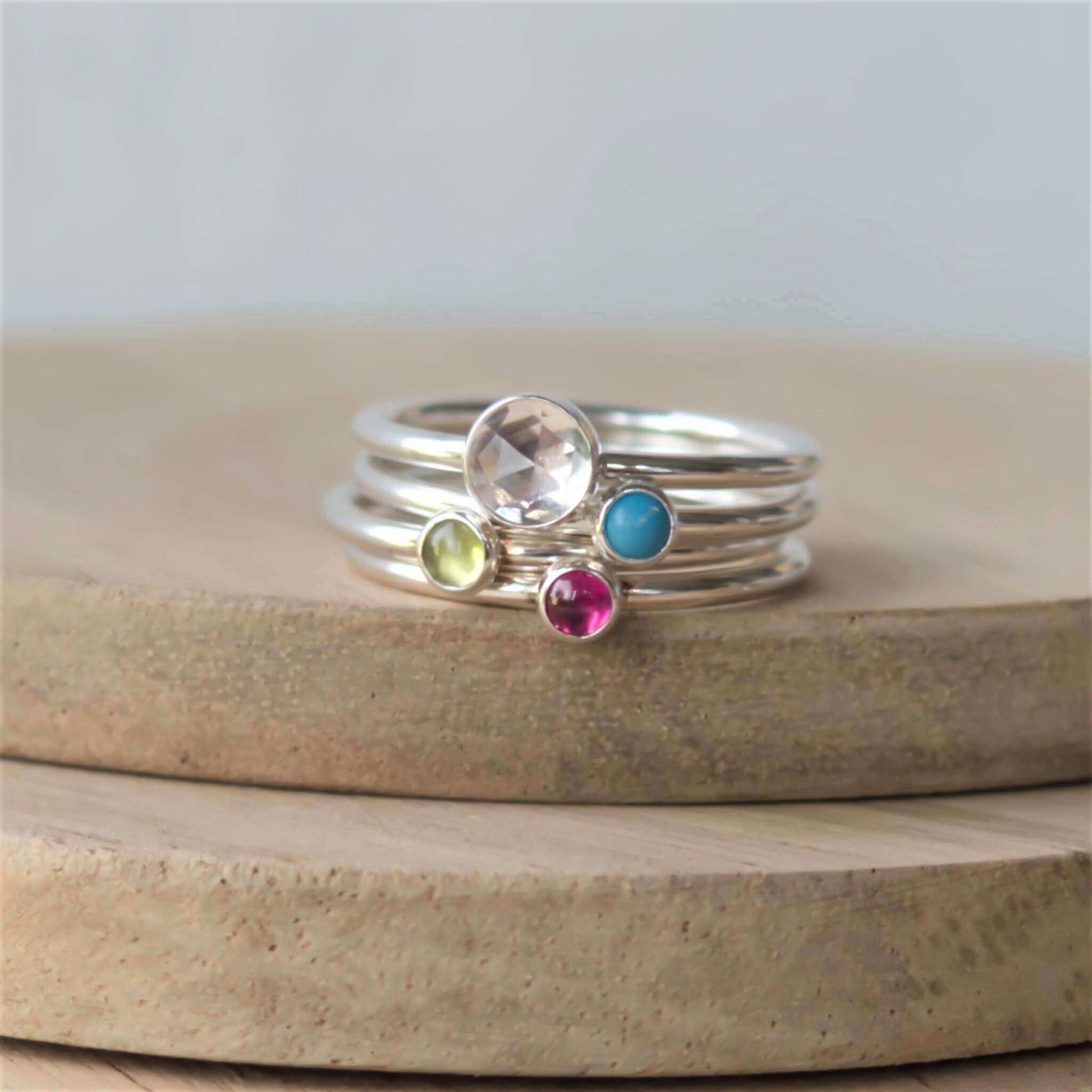 Four ring set of silver rings with different sized gemstones. Includes a 5mm facet clear topaz, turquoise, peridot and pink lab ruby all 3mm in size. Handmade by maram jewellery in Edinburgh