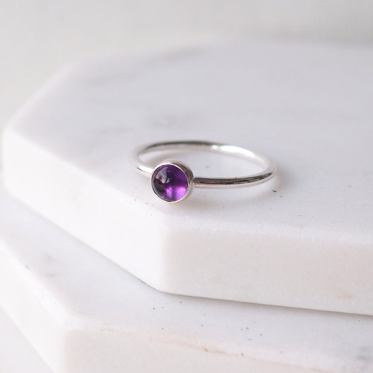 Single solitaire sterling silver ring with a round 5mm purple Amethyst. The ring is made in a modern simple style with a 5mm round cabochon set onto a modern halo fully round band. Made to order to your ring size, and handmade in Scotland by maram jewellery