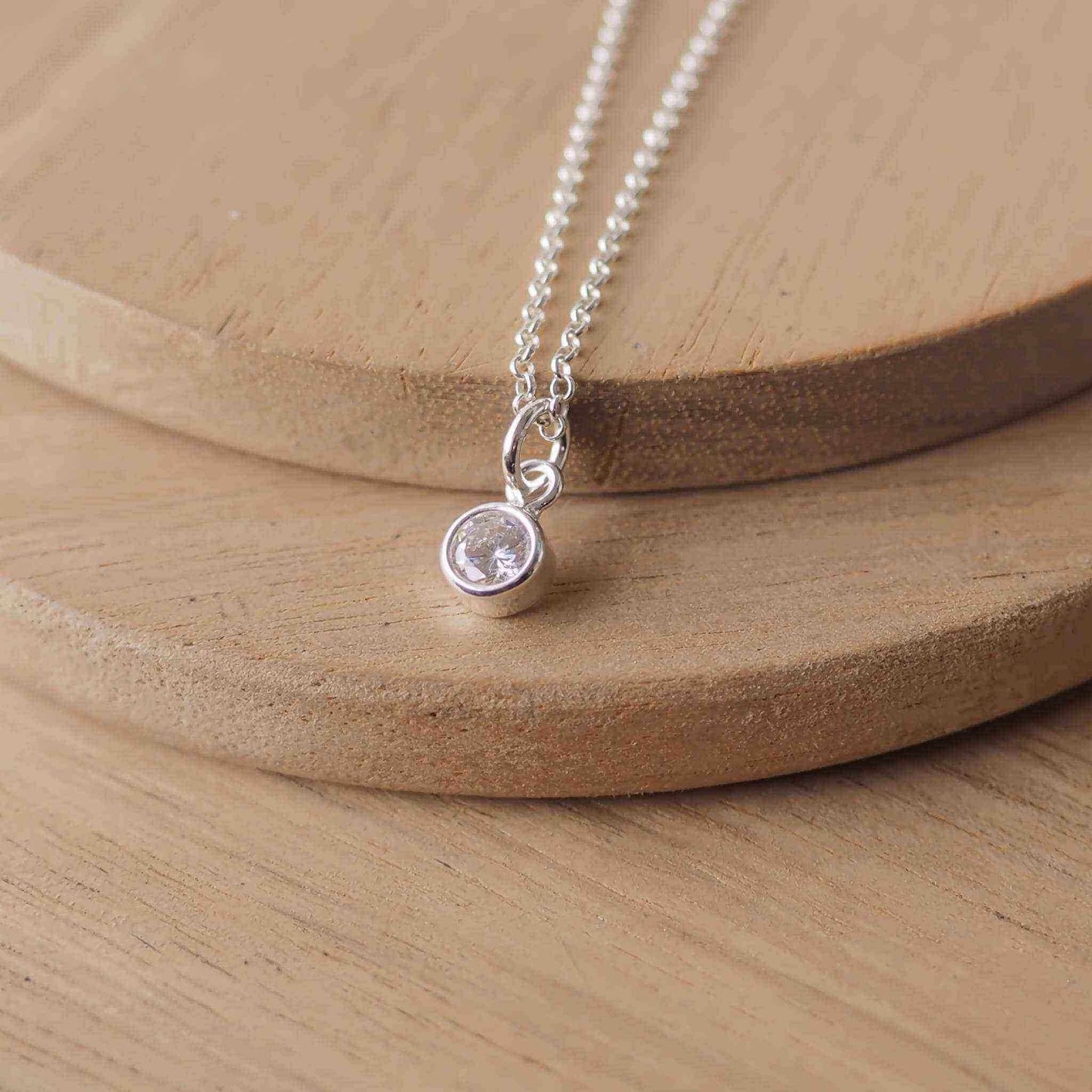Petite Sterling Silver and Cubic Zirconia Diamond necklace with April Birthstone. A small 4mm faceted round clear imitation  diamond gemstone with a simple silver setting on a trace style chain. Handmade in Scotland by Maram Jewellery