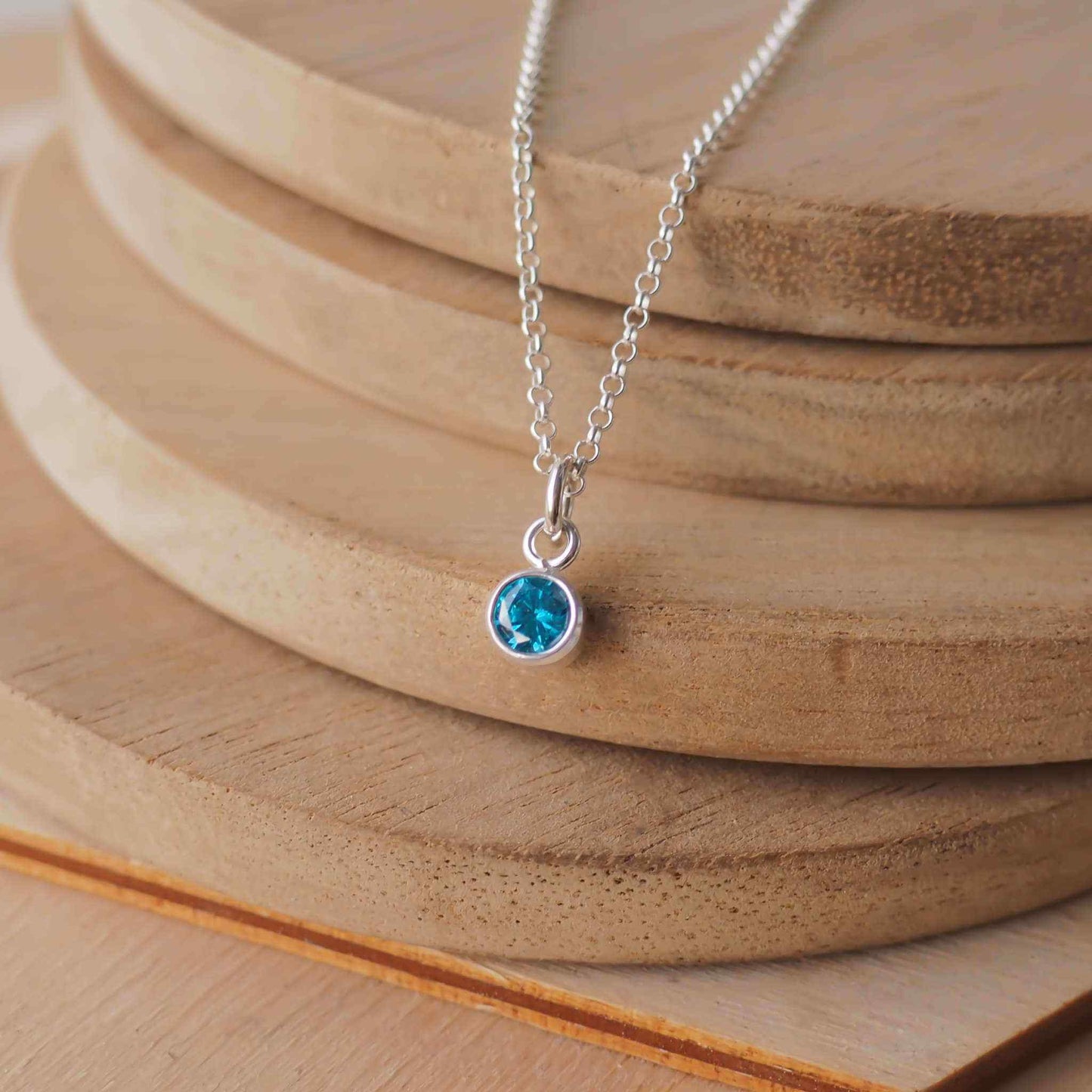 Petite Sterling Silver and Cubic Zirconia Blue Zircon necklace with December Birthstone. A small 4mm facet round rich blue gemstone with a simple silver setting on a trace style chain. Handmade in Scotland by Maram Jewellery