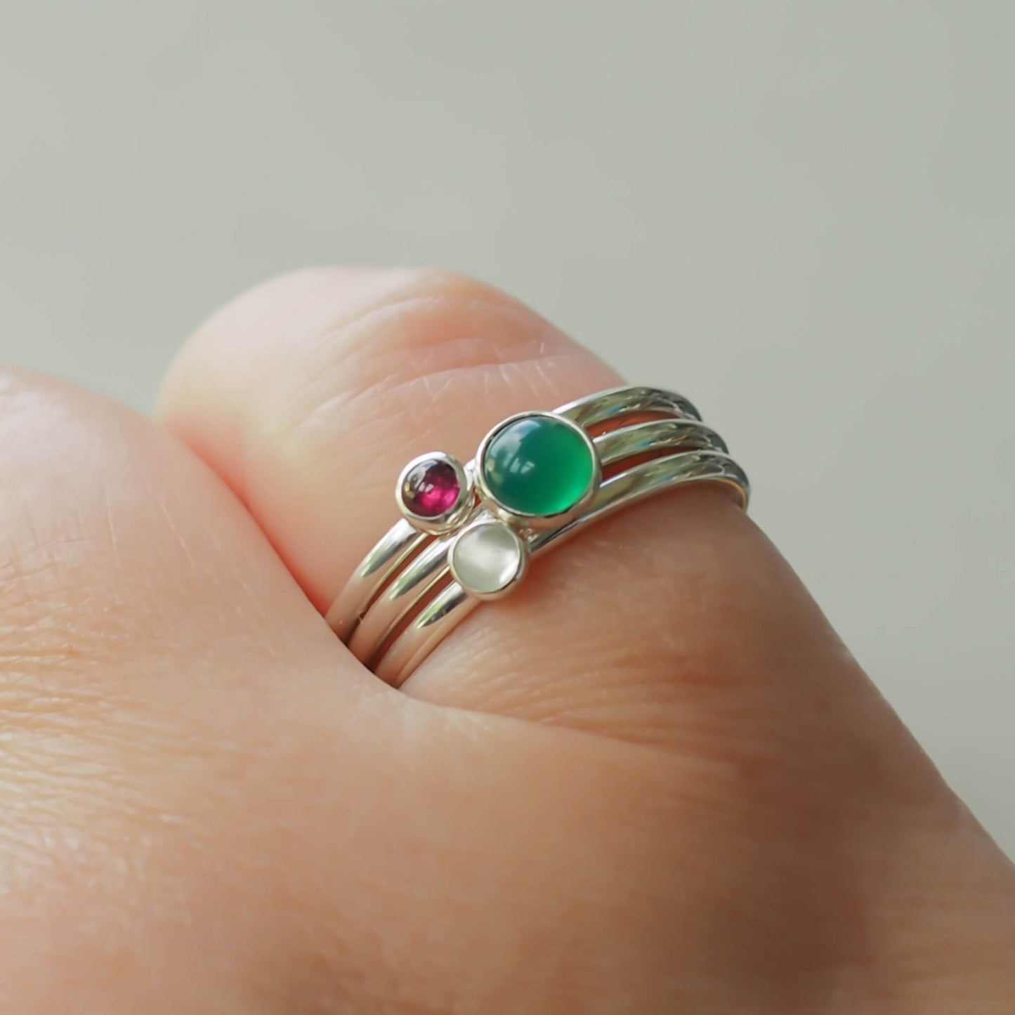 Three Birthstone Ring set made from Sterling Silver, with a 5mm round Green Agate Birthstone for May, and two smaller 3mm gemstones in Garnet for January, and Moonstone for June. The gemstones colours are emerald green, deep red and milky white. Handmade in Scotland by Maram Jewellery