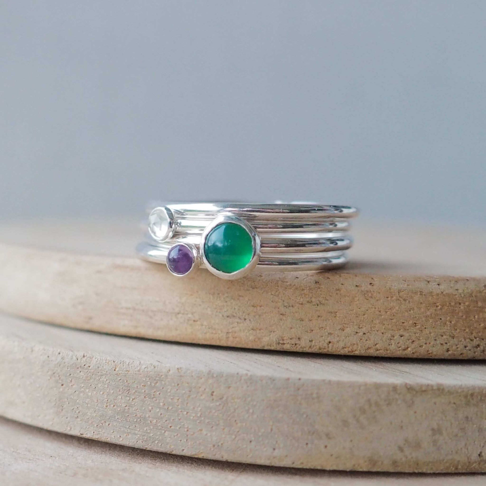 Three Birthstone Ring set made from Sterling Silver, with a 5mm round Green Agate Birthstone for May, and two smaller 3mm gemstones in White Topaz for April and Amethyst for February. The gemstones colours are emerald green, purple and clear. Handmade in Scotland by Maram Jewellery