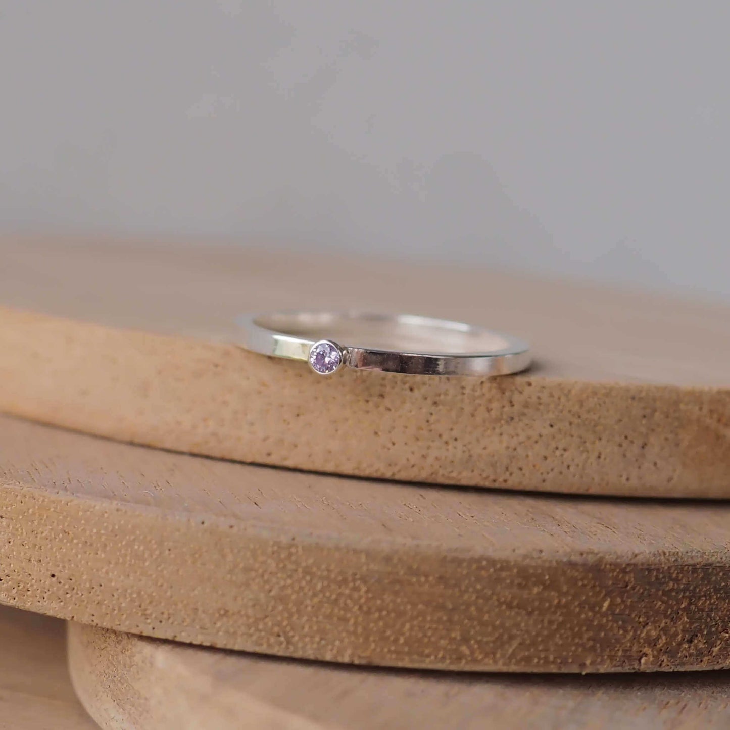 Silver ring with a light purple gemstone. The ring is simple in style with no embellishment , with a square band 1.5mm thick with a simple Lavender Alexandrite 2mm round cubic zirconia stone set in an enclosed silver setting. The gem is very small and minimal on the band. Alexandrite is birthstone for June. The ring is Sterling Silver and made to your ring size. Handmade in Scotland by Maram Jewellery