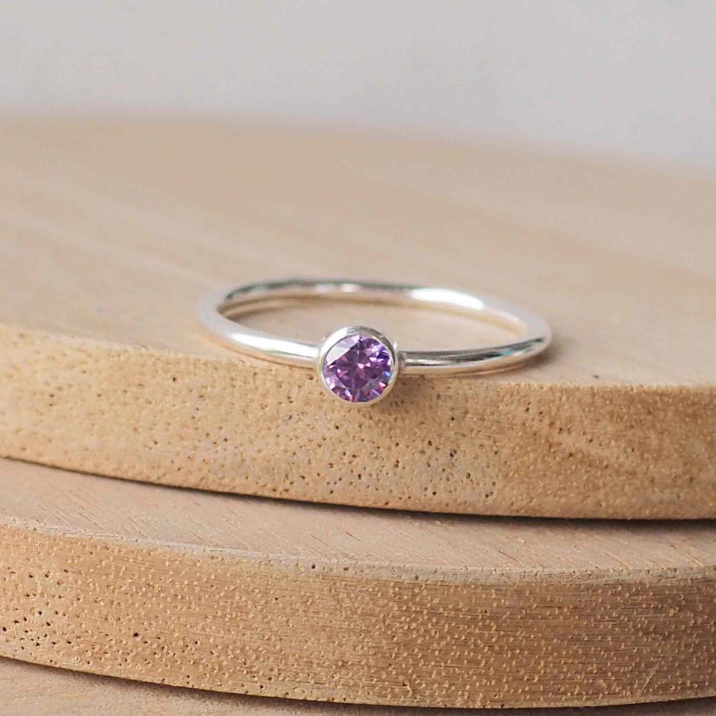 Silver ring with a Purple gemstone. The ring is simple in style with no embellishment , with a round wire band 1.5mm thick with a simple Deep Purple Amethyst 4mm round cubic zirconia stone set in an enclosed silver setting. Amethyst is birthstone for February. The ring is Sterling Silver and made to your ring size. Handmade in Scotland by Maram Jewellery
