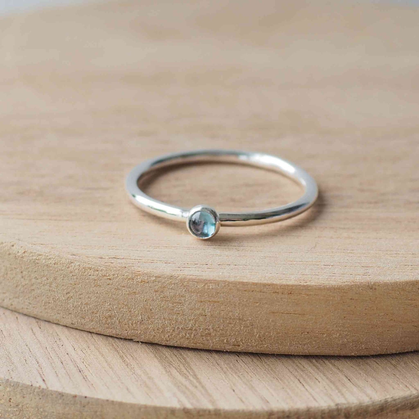 Small gemstone ring in sterling silver with a modern round band with a 3mm sized round light blue Aquamarine. Handmade in Edinburgh by Maram Jewellery