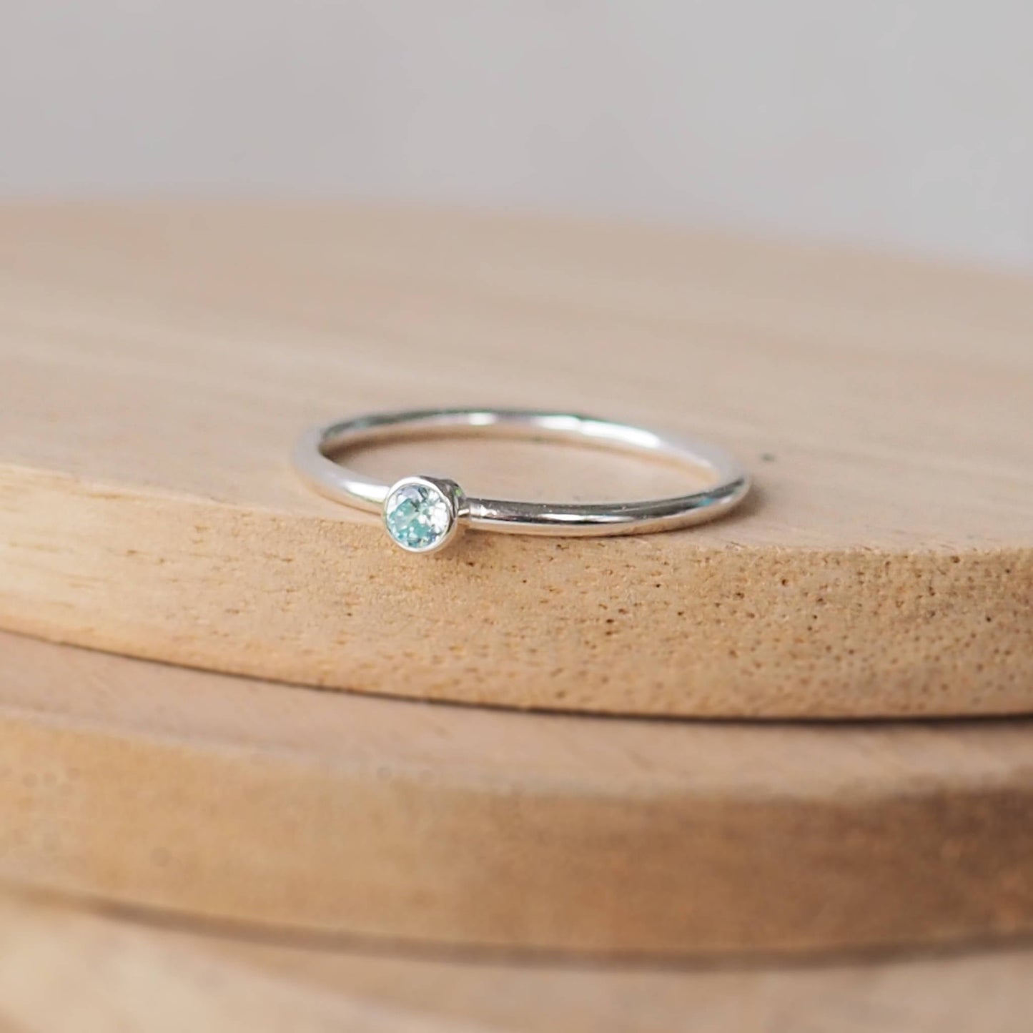 Aquamarine and Sterling Silver solitaire ring with an aqua coloured round cubic zirconia measuring 3mm in size. A very simple minimalist ring made from Sterling Silver on a halo style band. Handmade in Scotland by maram jewellery