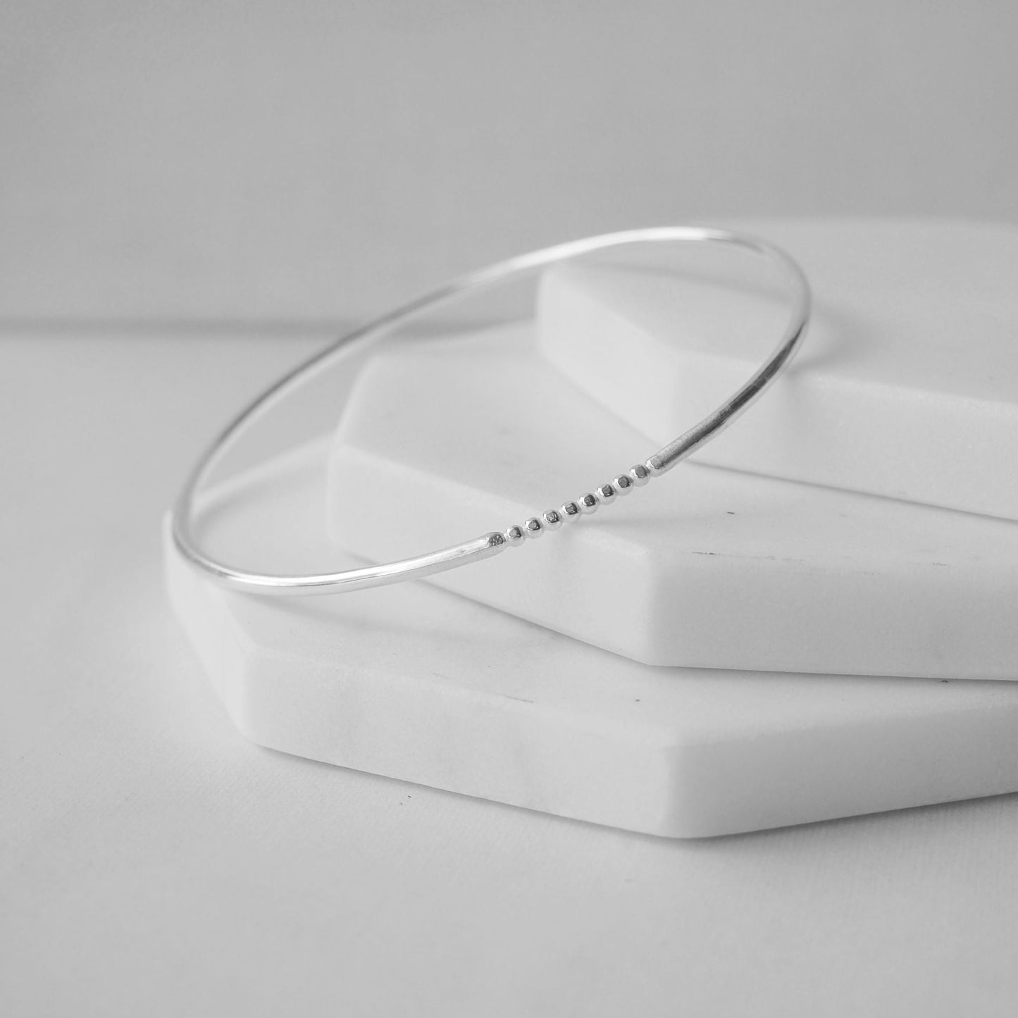 Silver bangle made by maram jewellery in Scotland UK. Made in a round halo profile with a fixed beaded section. THese bangles are made with leftover sections on silver so are eco friendly. Made in Scotland UK