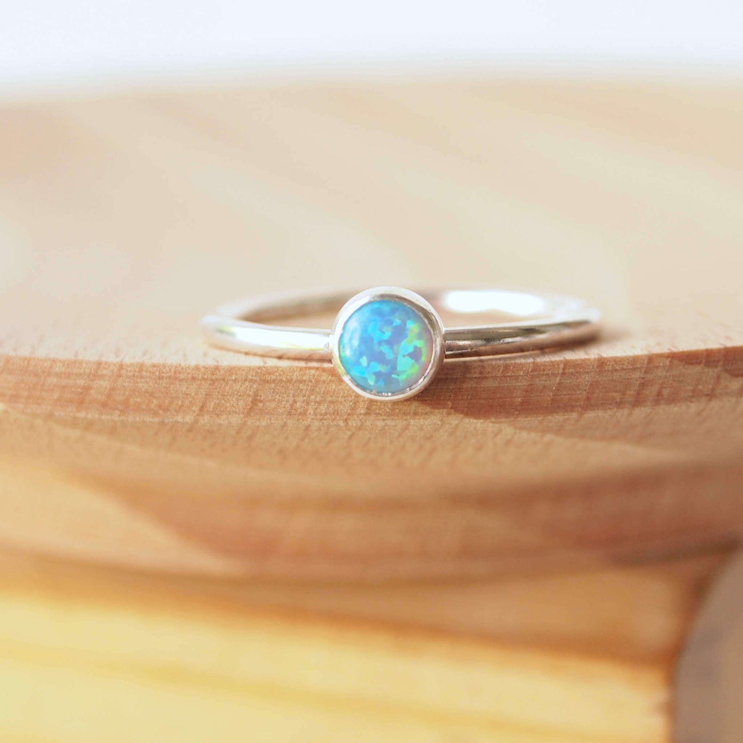 Simple style Lab Opal and Sterling Silver single Solitaire Ring with Lab Opal. Opal is Birthstone for October. The round 5mm gem is a blue opal with lots of iridescence. Handmade by Maram Jewellery in Scotland