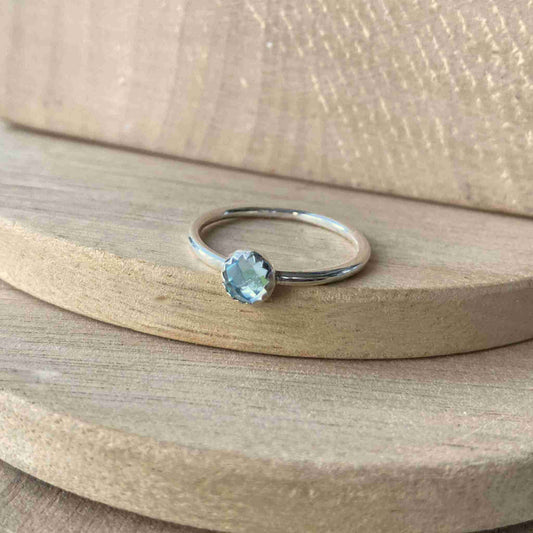 Blue Topaz and Sterling Silver Birthstone RIng for March. The ring is simple in style on a plain fully round band with a small round facet cut pale blue topaz in the centre. The ring is handmade to your size by maram jewellery in Scotland