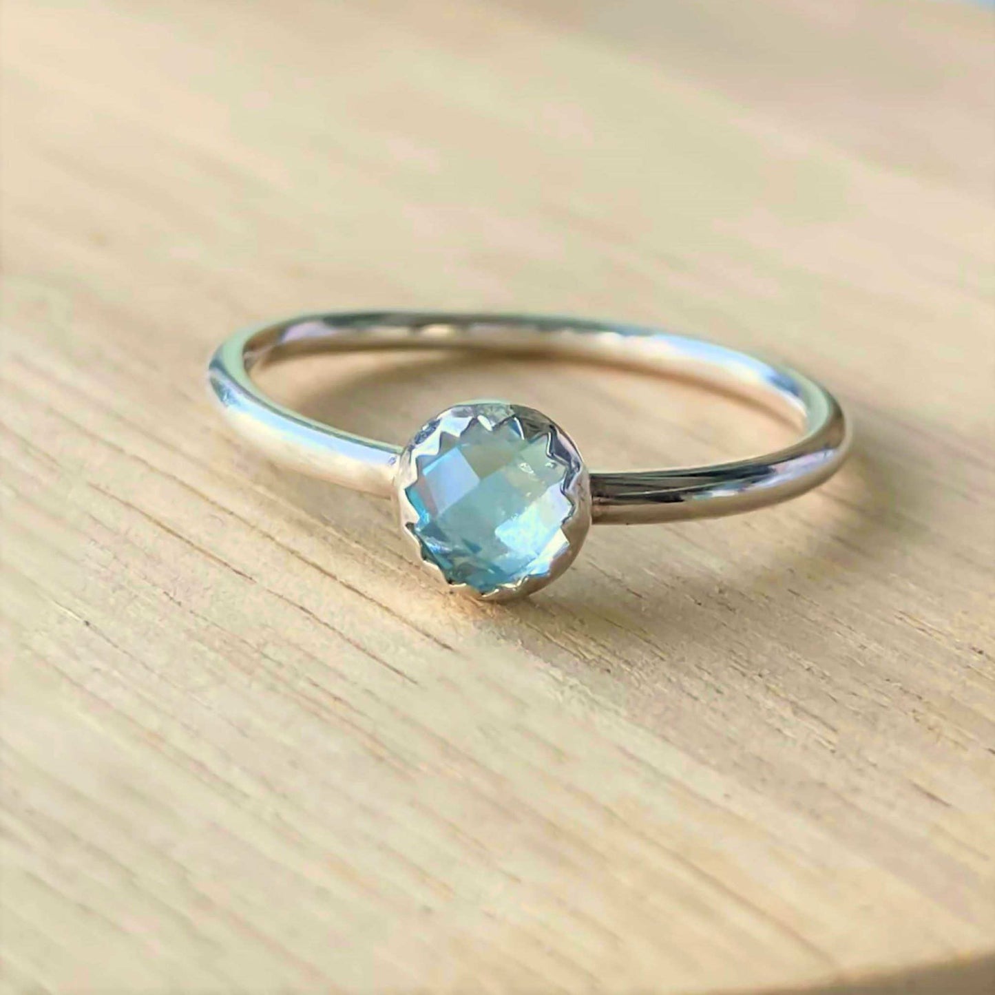 Blue Topaz and Sterling Silver Birthstone RIng for March. The ring is simple in style on a plain fully round band with a small round facet cut pale blue topaz in the centre. The ring is handmade to your size by maram jewellery in Scotland