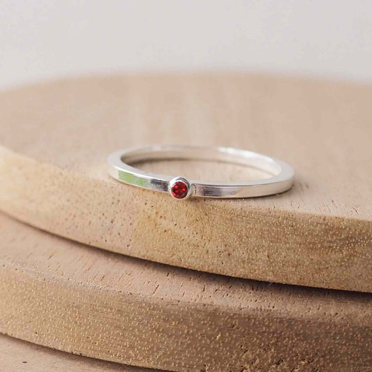 Garnet and Sterling Silver solitaire ring with a deep red coloured round cubic zirconia measuring 2mm in size. A very simple minimalist ring made from Sterling Silver on a minimalist square style band. Handmade in Scotland by maram jewellery