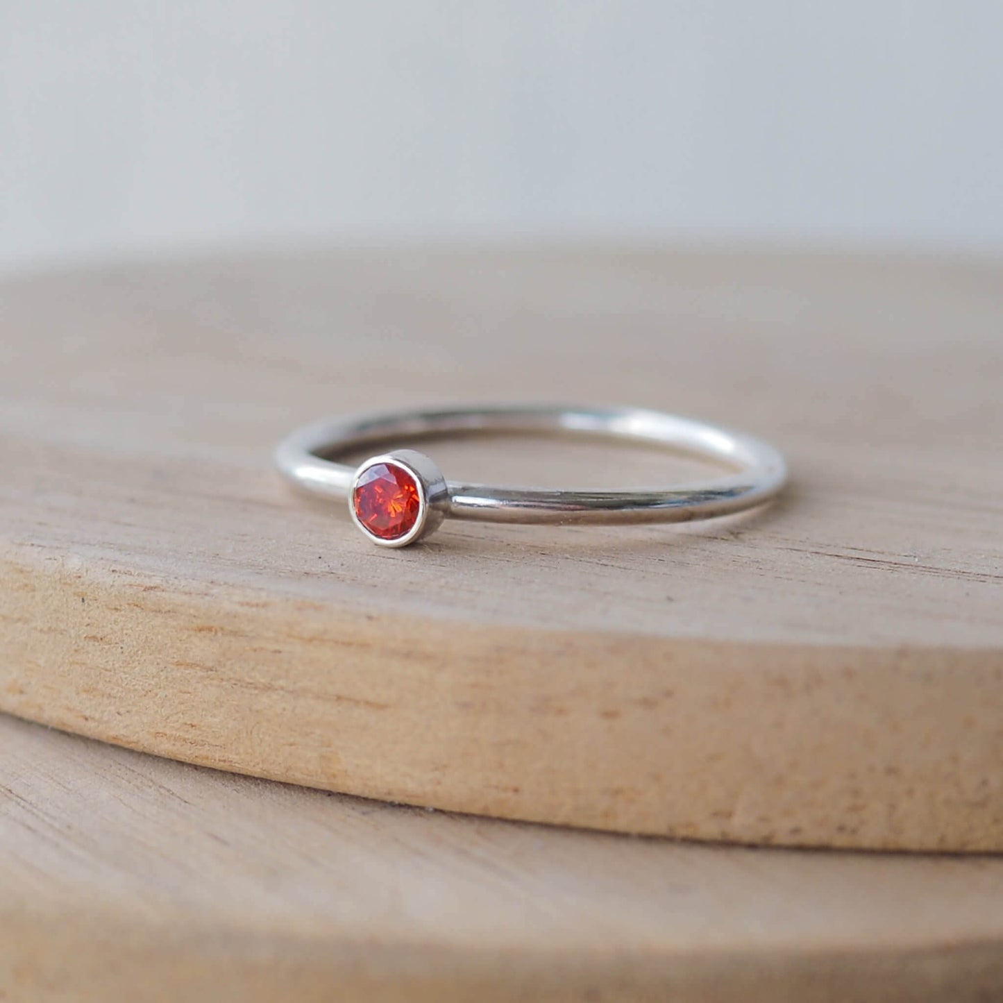 Garnet and silver minimalist solitaire ring. Made from a modern band of square silver wire with a simple round red faceted cubic zirconia. Handmade in Scotland by Maram Jewellery