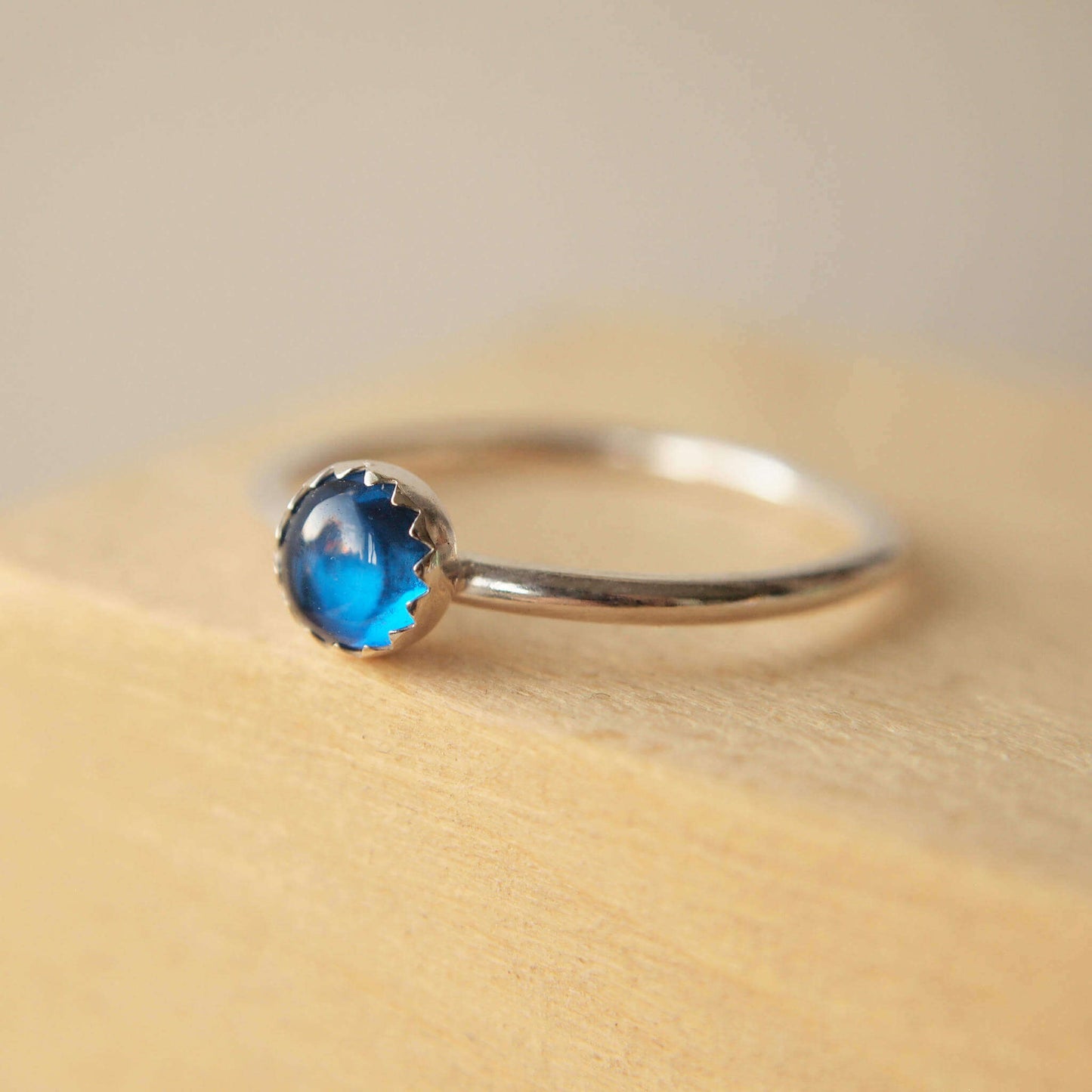 Simple styled silver and blue gemstone ring with a lab sapphire round stone on a silver band. The ring is made from a 5mm round cabochon in bright blue. Handmade to your choice of ring size by maram jewellery in Scotland