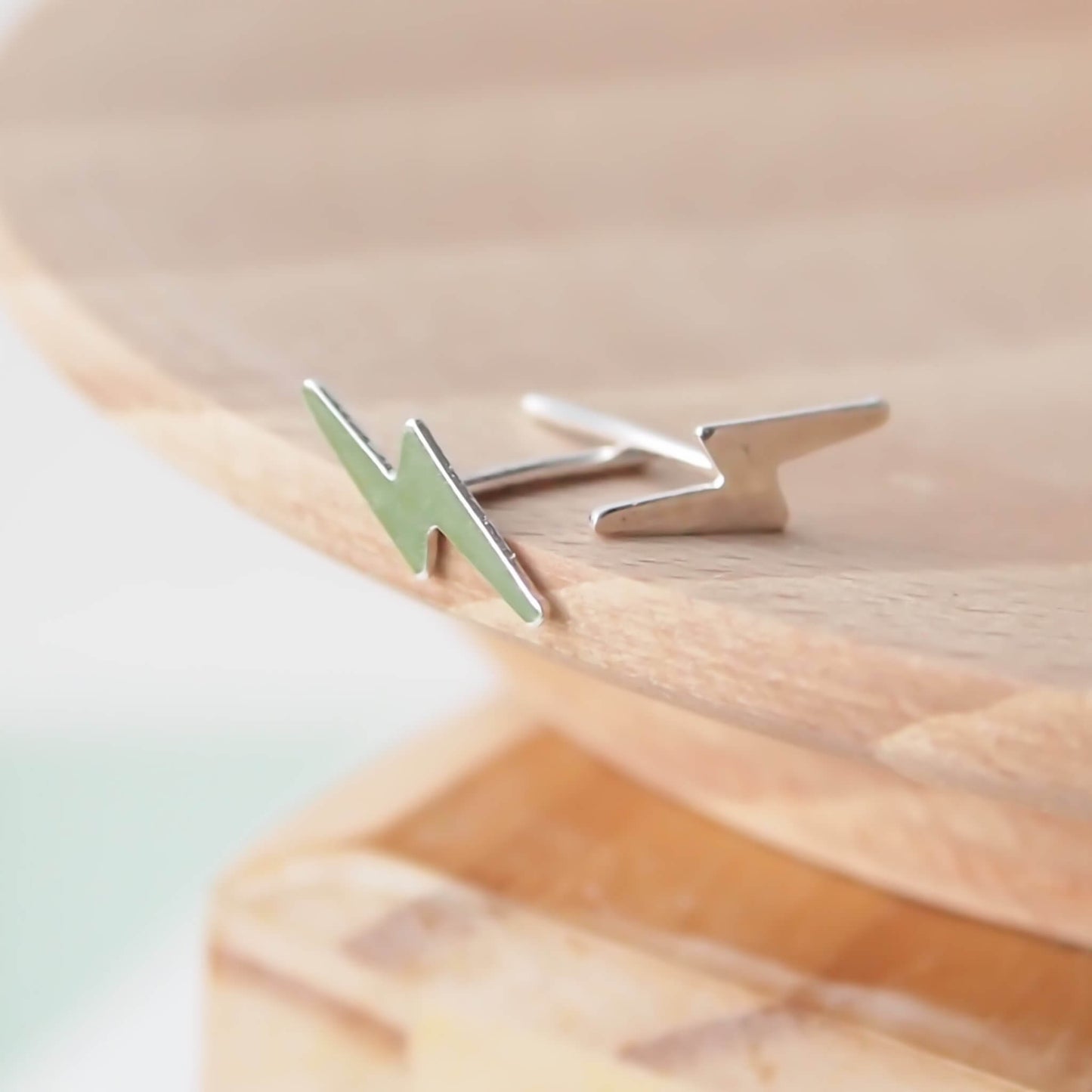Sterling SIlver lightning bolt earring worn pictured on a wooden background. handmade by maram jewellery in Edinburgh UK