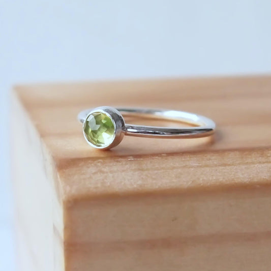 Sterling Silver and pale green Peridot gemstone, a round facet cut cabochon. Simple and minimalist in style. Handmade Jewellery in Edinburgh UK