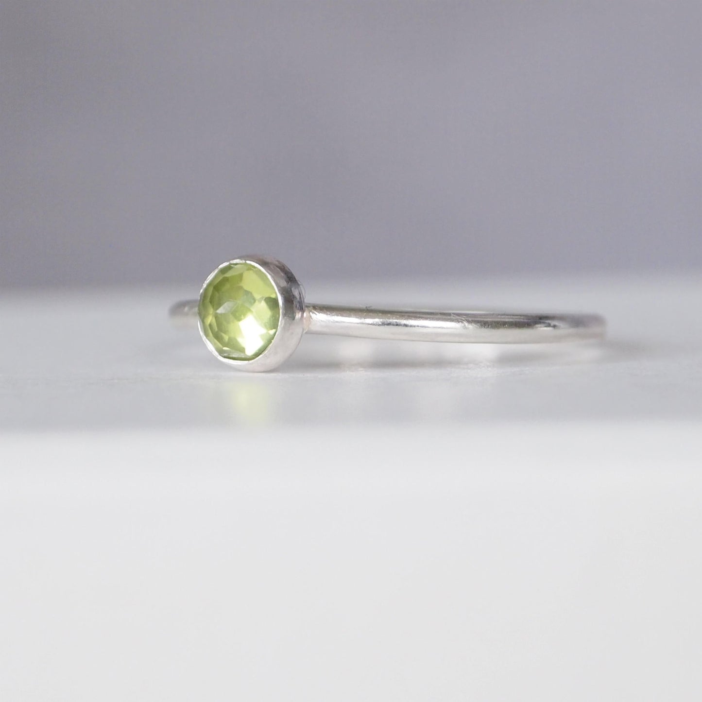 Sterling Silver and pale green Peridot gemstone, a round facet cut cabochon. Simple and minimalist in style. Handmade Jewellery in Edinburgh UK