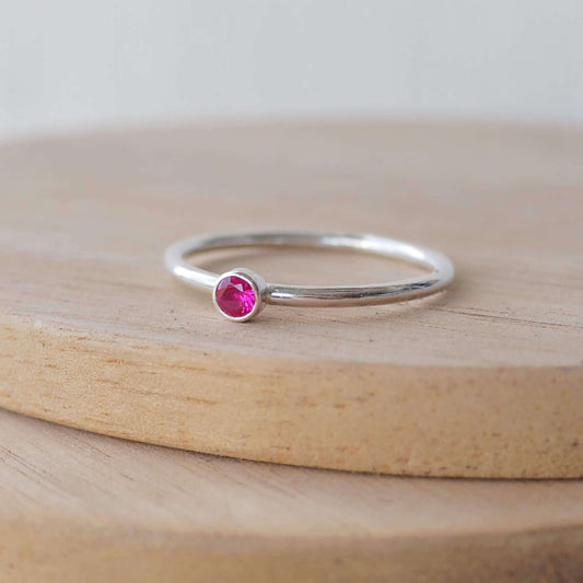 Silver ring with a pinky red gemstone. The ring is simple in style with no embellishment , with a round wire band 1.5mm thick with a simple ruby coloured 3mm round cubic zirconia stone set in an enclosed silver setting. Ruby is birthstone for July. The ring is Sterling Silver and made to your ring size. Handmade in Scotland by Maram Jewellery