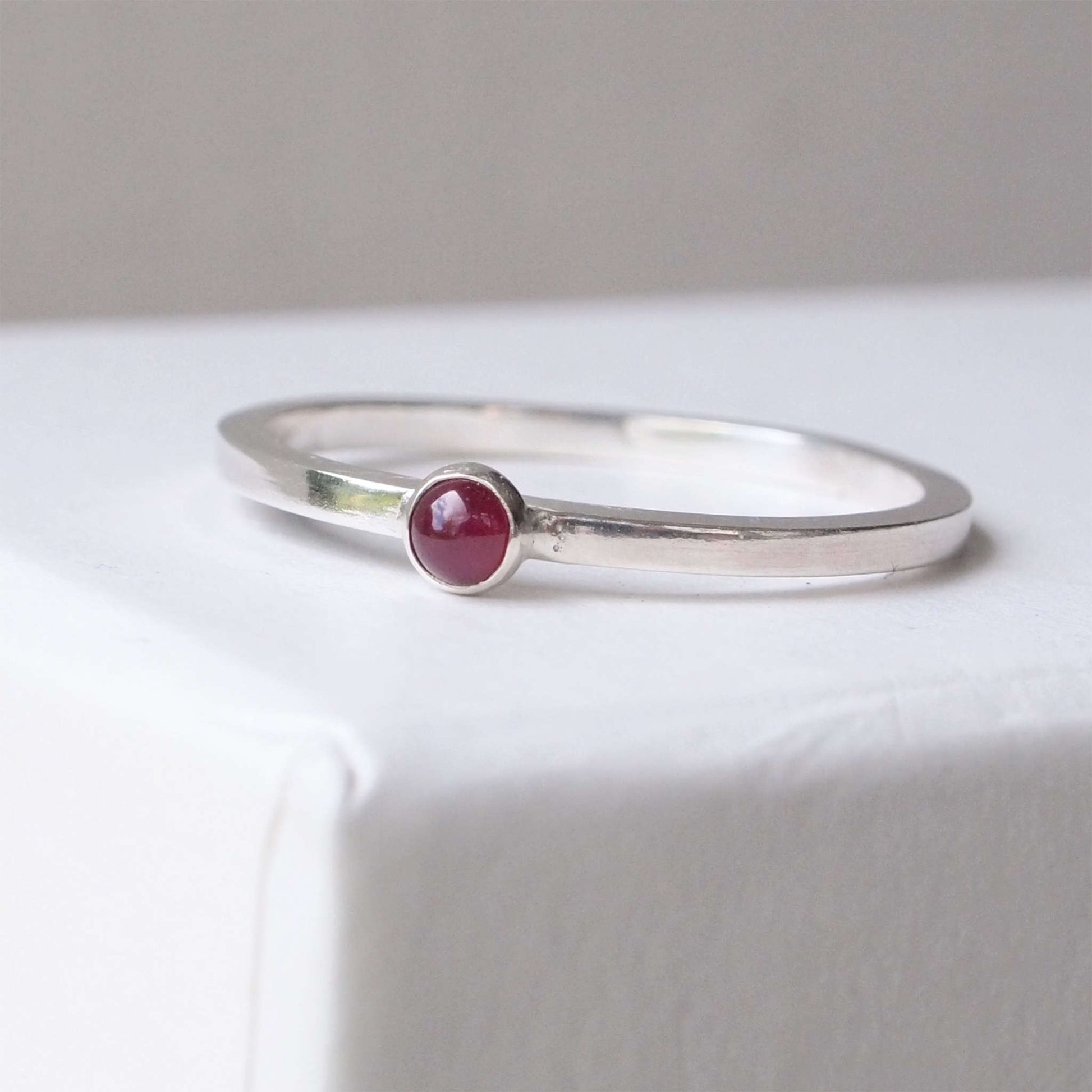 Ruby and Sterling Silver Birthstone Ring for July. The ring is simple in style on a plain square profile band with a small round Ruby in the centre. The ring is handmade to your size by maram jewellery in Scotland