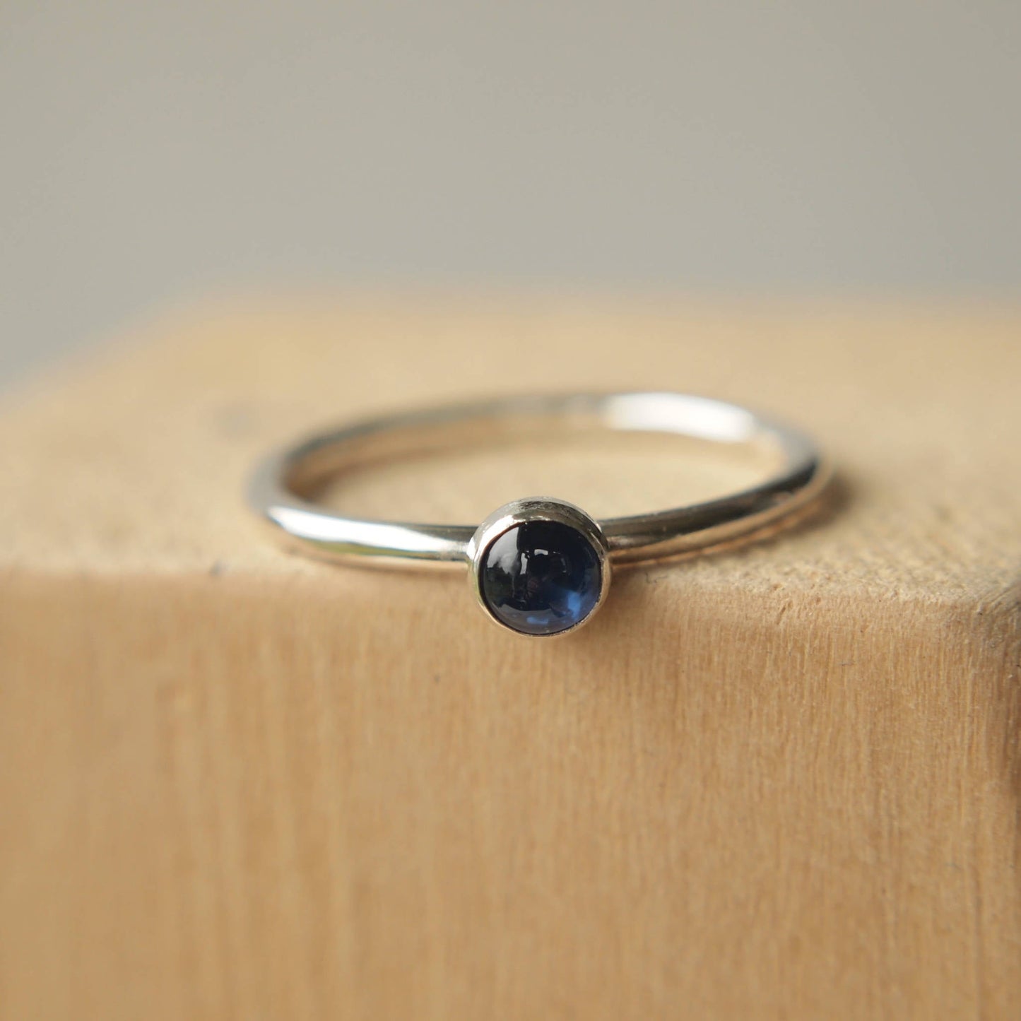 Simple Solitaire ring with a genuine Sapphire gemstone. The ring is made from Sterling Silver and a round natural sapphire measuring 4mm in size. It is set onto a modern ring with a fully round profile. The ring is handmade to your ring size  by maram jewellery in Scotland UK