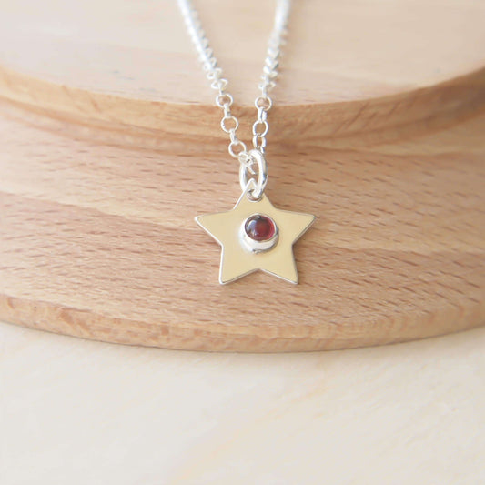 Small Silver Star Charm necklace with a deep red garnet centre. On a simple silver chain to create a necklace for all ages. Handmade by maram jewellery in UK