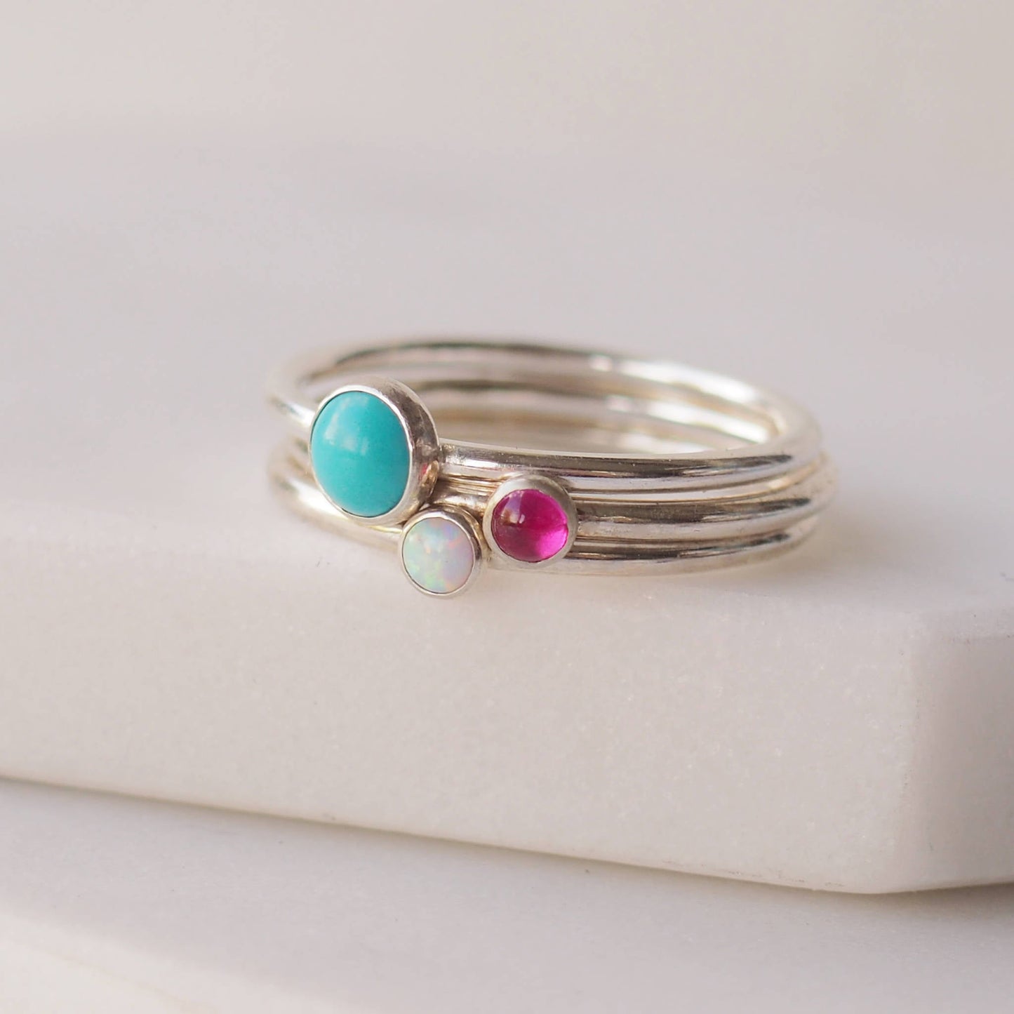 Three ring birthstone set with a large Turquoise, smaller Lab Opal and Lab Ruby. Handmade by maram jewellery in Scotland UK
