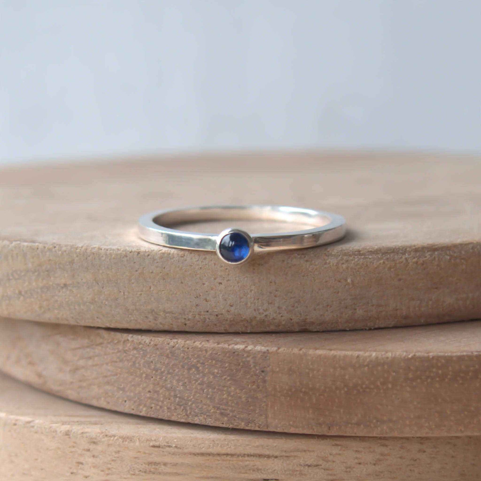 Simple Sapphire gemstone ring in sterling silver with a modern square band with a 3mm sized round Blue Sapphire Cabochon. Handmade in Edinburgh by Maram Jewellery