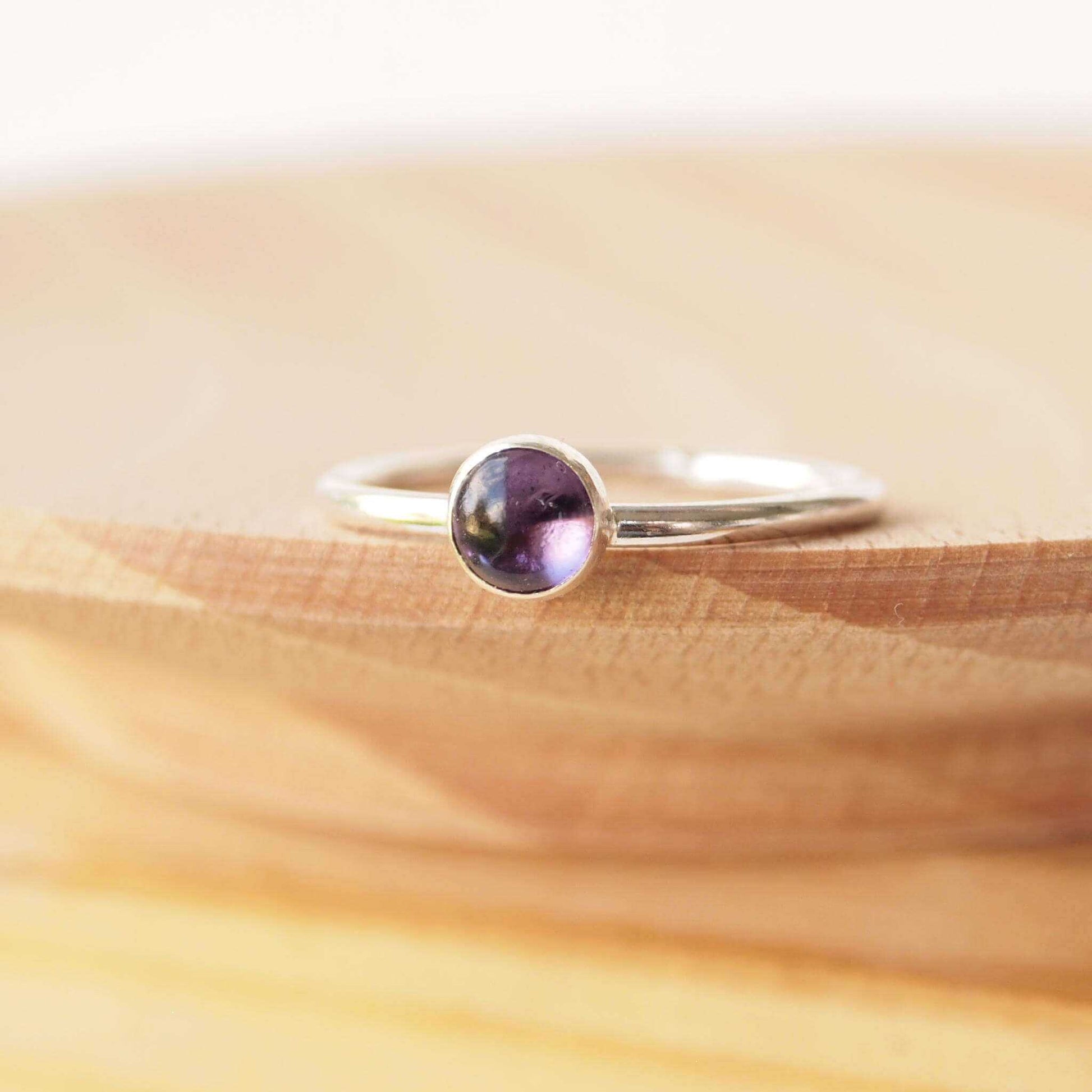 Single solitaire sterling silver ring with a round 5mm purple Amethyst. The ring is made in a modern simple style with a 5mm round cabochon set onto a modern halo fully round band. Made to order to your ring size, and handmade in Scotland by maram jewellery