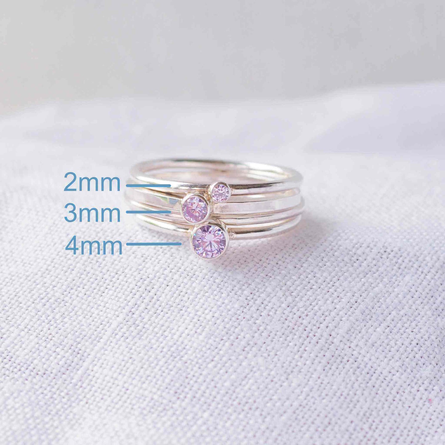 Three rings showing the square and round band styles with three different sized Cubic Zirconia in a pale Lavender Alexandrite colour. The rings are made from Sterling Silver and a round pale purple cubic zirconia measuring 2,3 or 4mm in size. Handmade by maram jewellery in Scotland