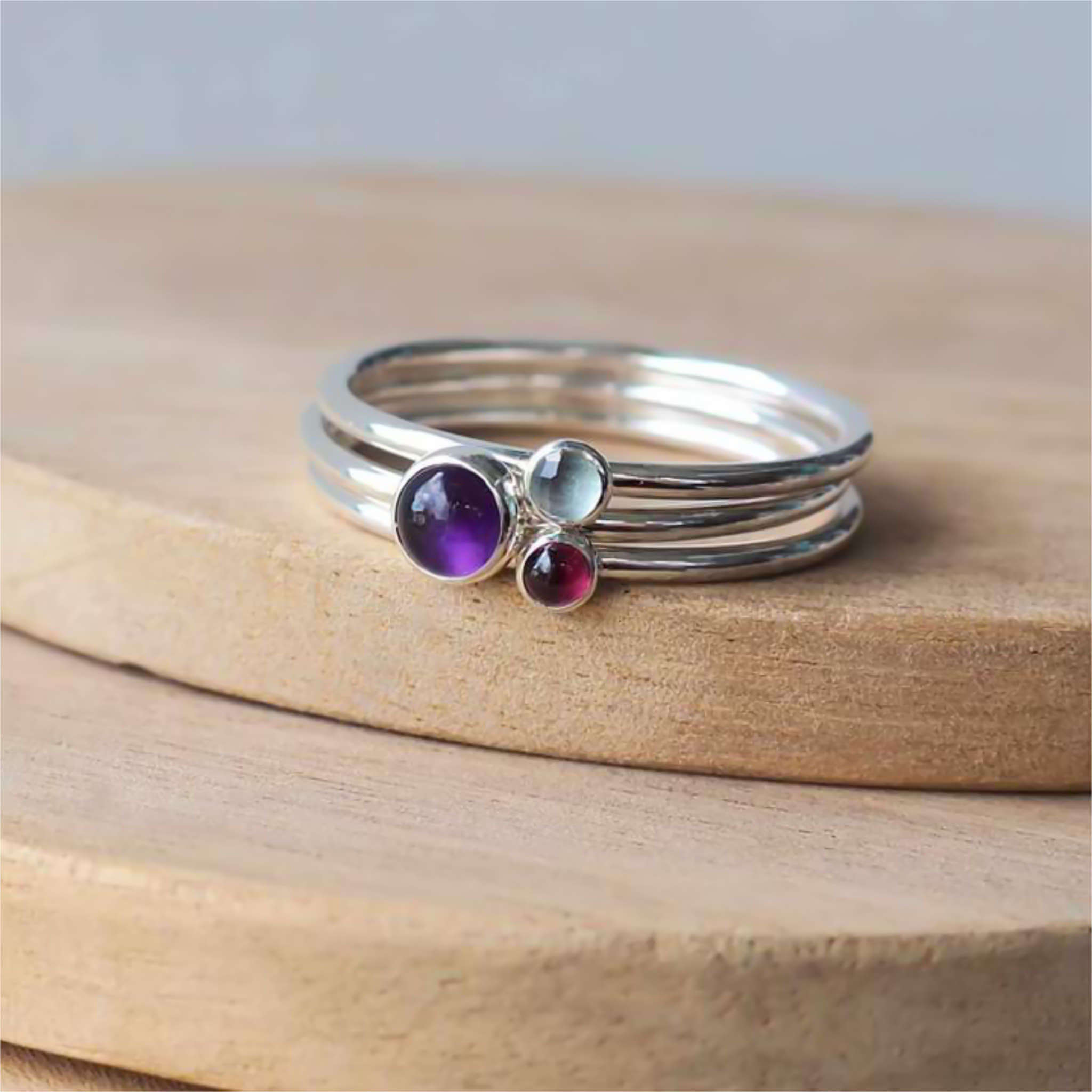 Three ring set made from Sterling Silver and assorted Birthstones. Set has a 5mm Amethyst ring, and two 3mm rings in Garnet and Blue topaz. Handmade in Scotland by Maram Jewellery