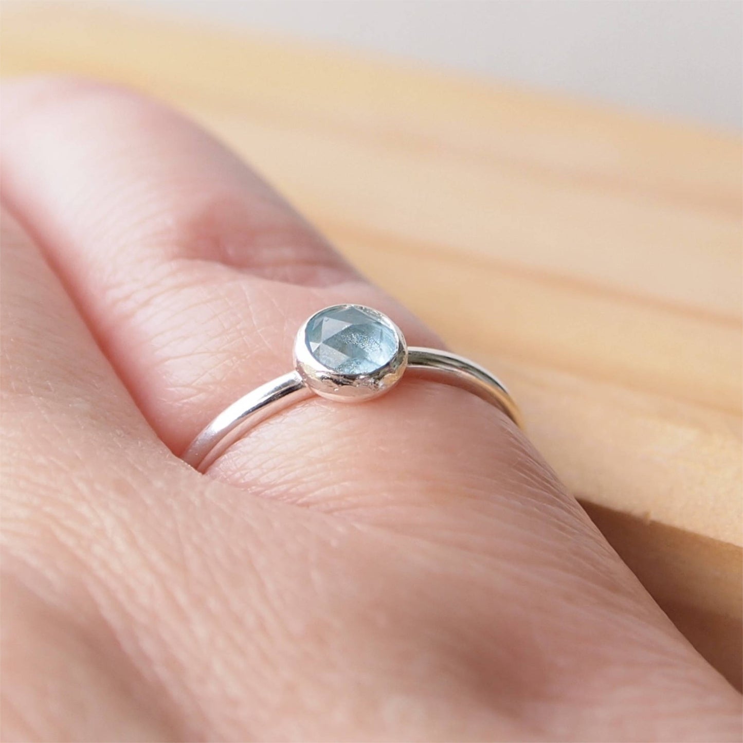 Simple style Aquamarine Silver ring with a round facet cut aquamarine cabochon pictured worn on hand. Made by maram jewellery