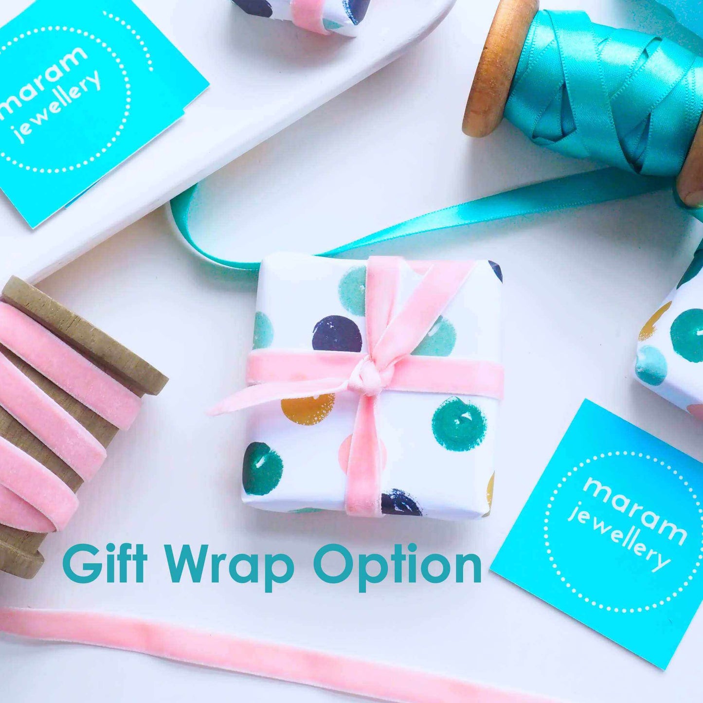 Ring box wrapped with luxury white gift wrap with coloured dots in green, gold and pink, tied neatly with a ribbon. Gift wrap option for maram jewellery with text