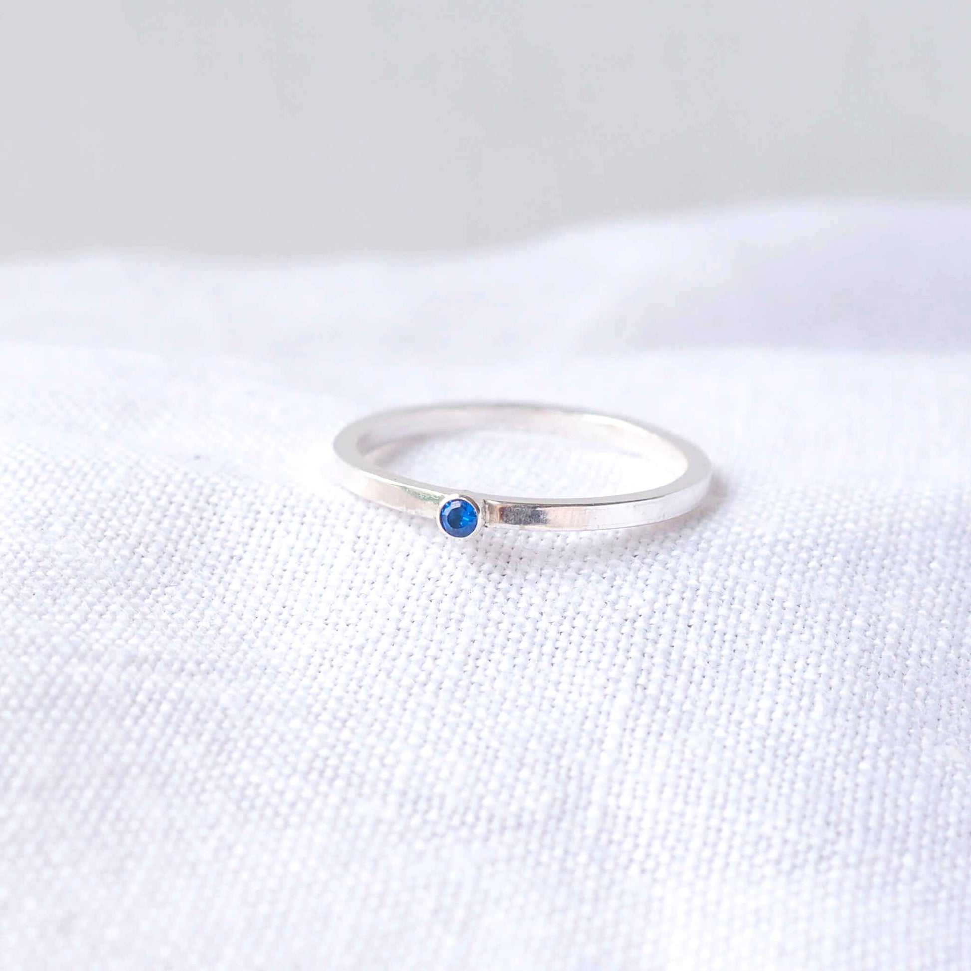 Silver and Blue Cubic Zirconia ring on a modern round square band with a small gemstone. The gem is a 2mm round cubic zirconila with pleny of sparkle. Handmade in Scotland by maram jewellery