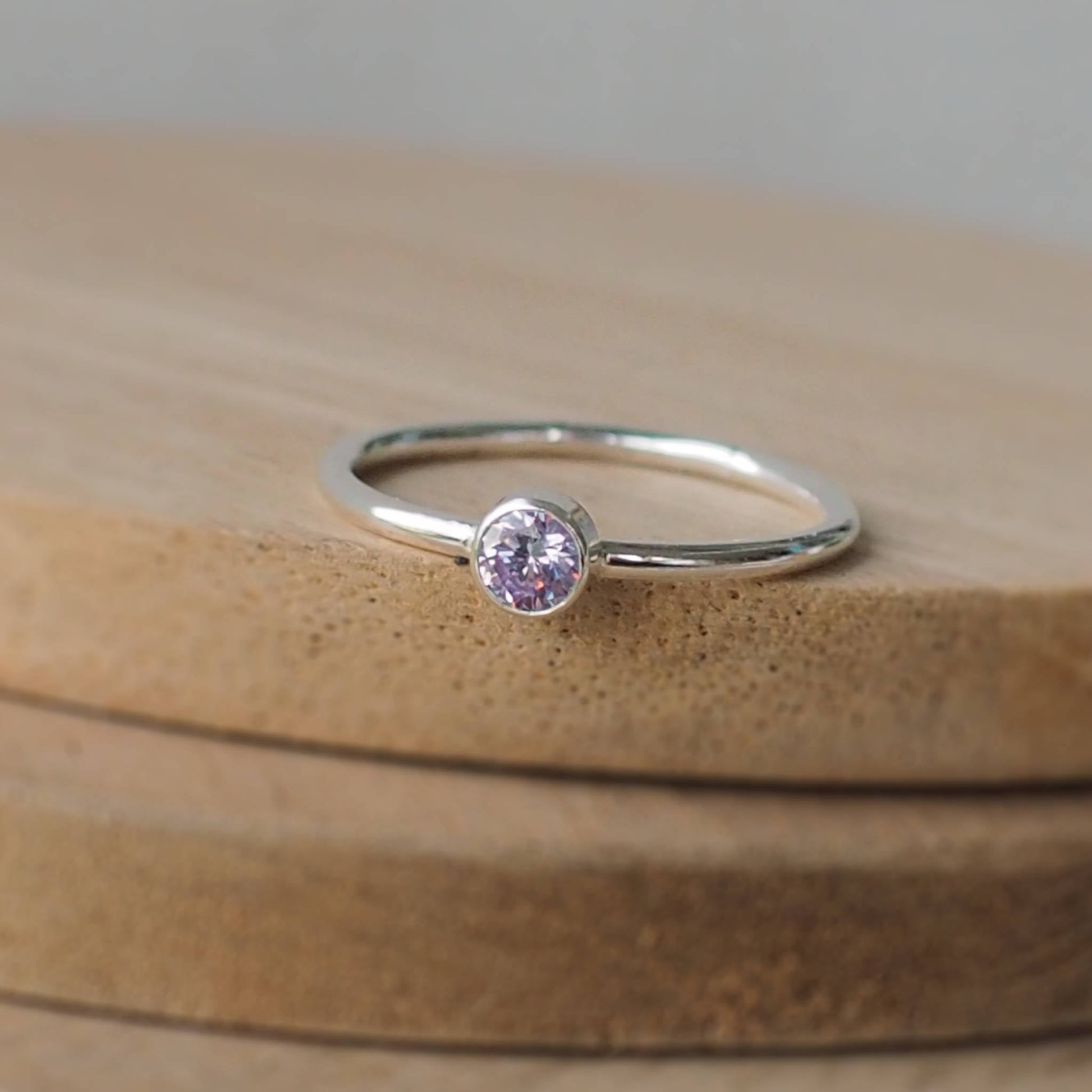 Silver ring with a Lavender Cubic Zirconia gemstone. The ring is simple in style with no embellishment , with a round wire band 1.5mm thick with a simple light purple alexandrite substitute 4mm round cubic zirconia stone set in an enclosed silver setting. Birthstone for June. The ring is Sterling Silver and made to your ring size. Handmade in Scotland by Maram Jewellery