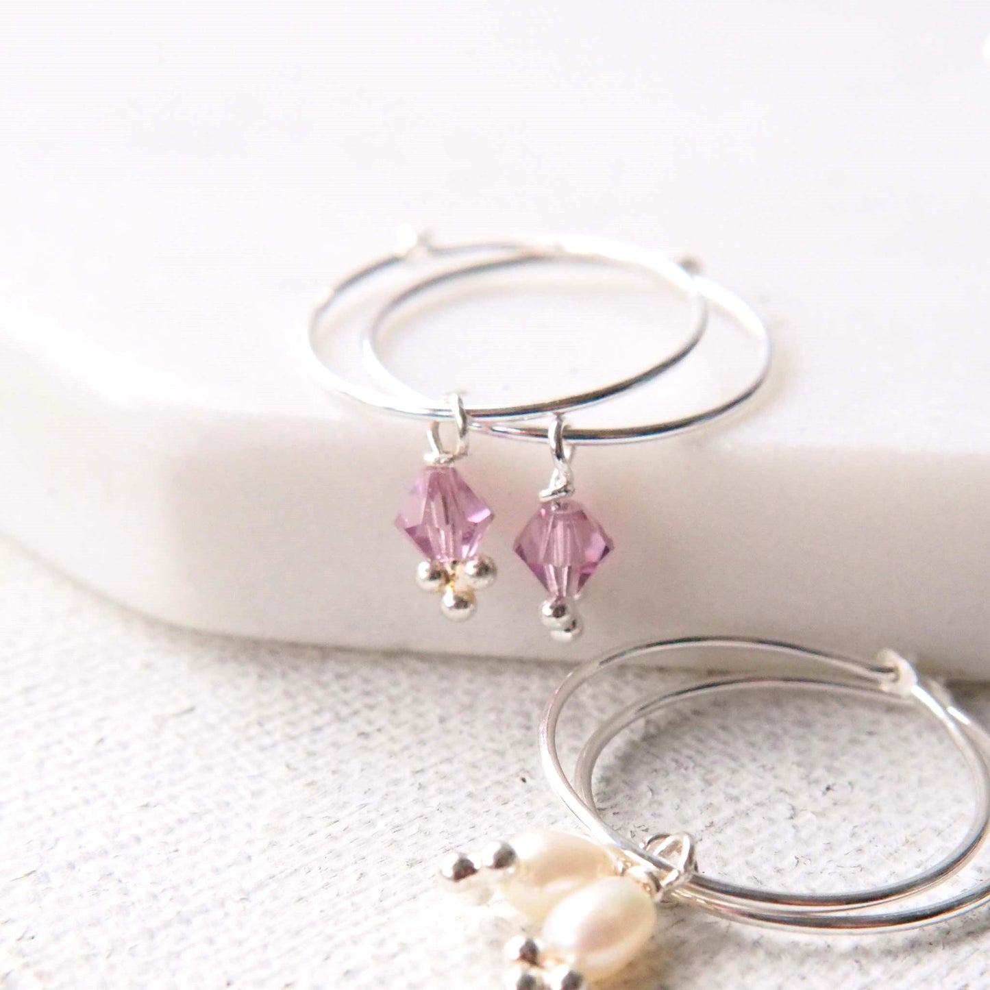 Alexandrite birthstone Hoops for June. Small dusky pink crystal and freshwater pearl charm drops on a thin sterling silver wire hoop. Handmade in Scotland by maram jewellery.
