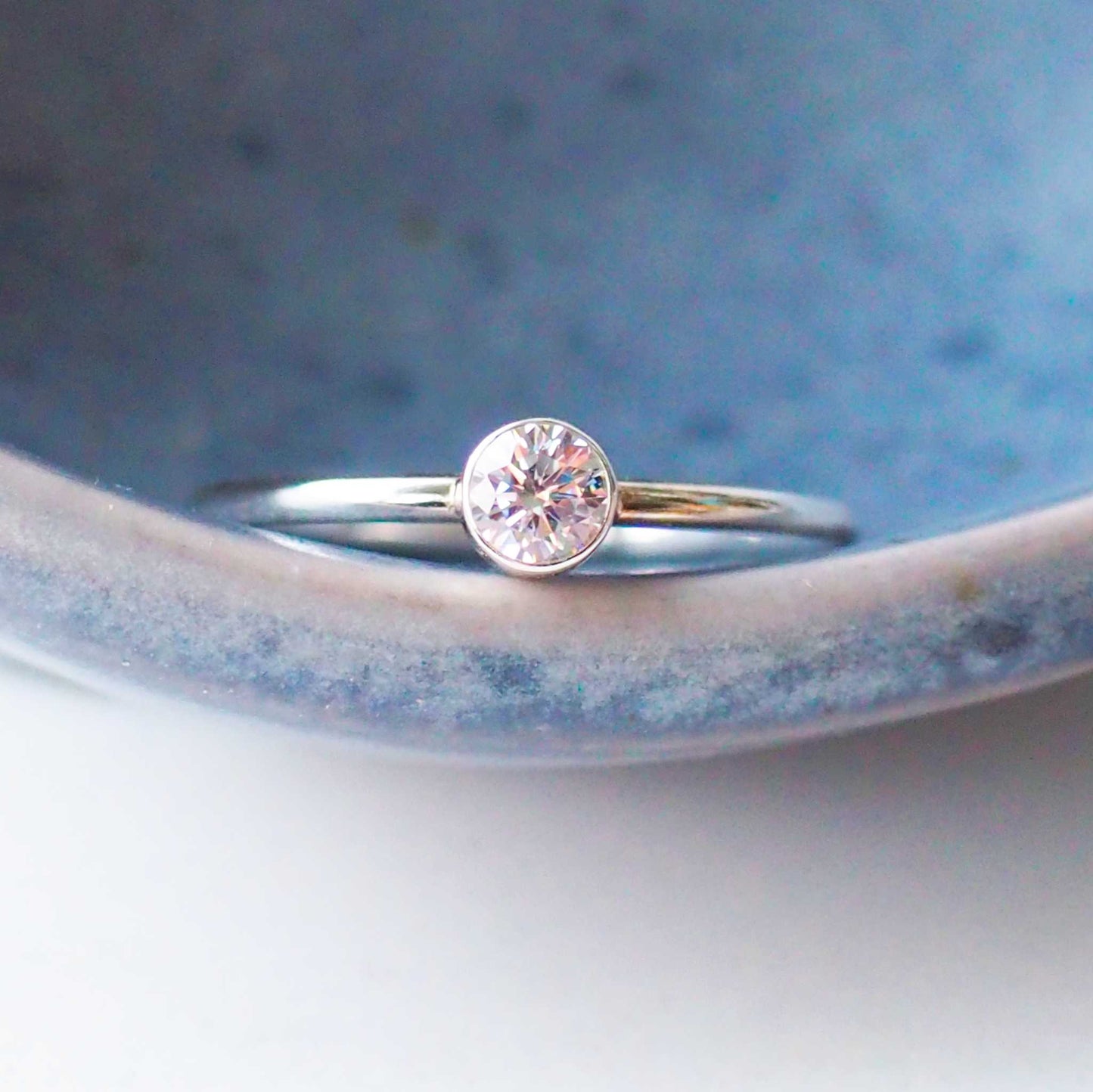 Silver and imitation diamond cubic zirconia ring in sterling silver on a blue pottery style background. a handmade ring by maram jewellery handcrafted in Scotland