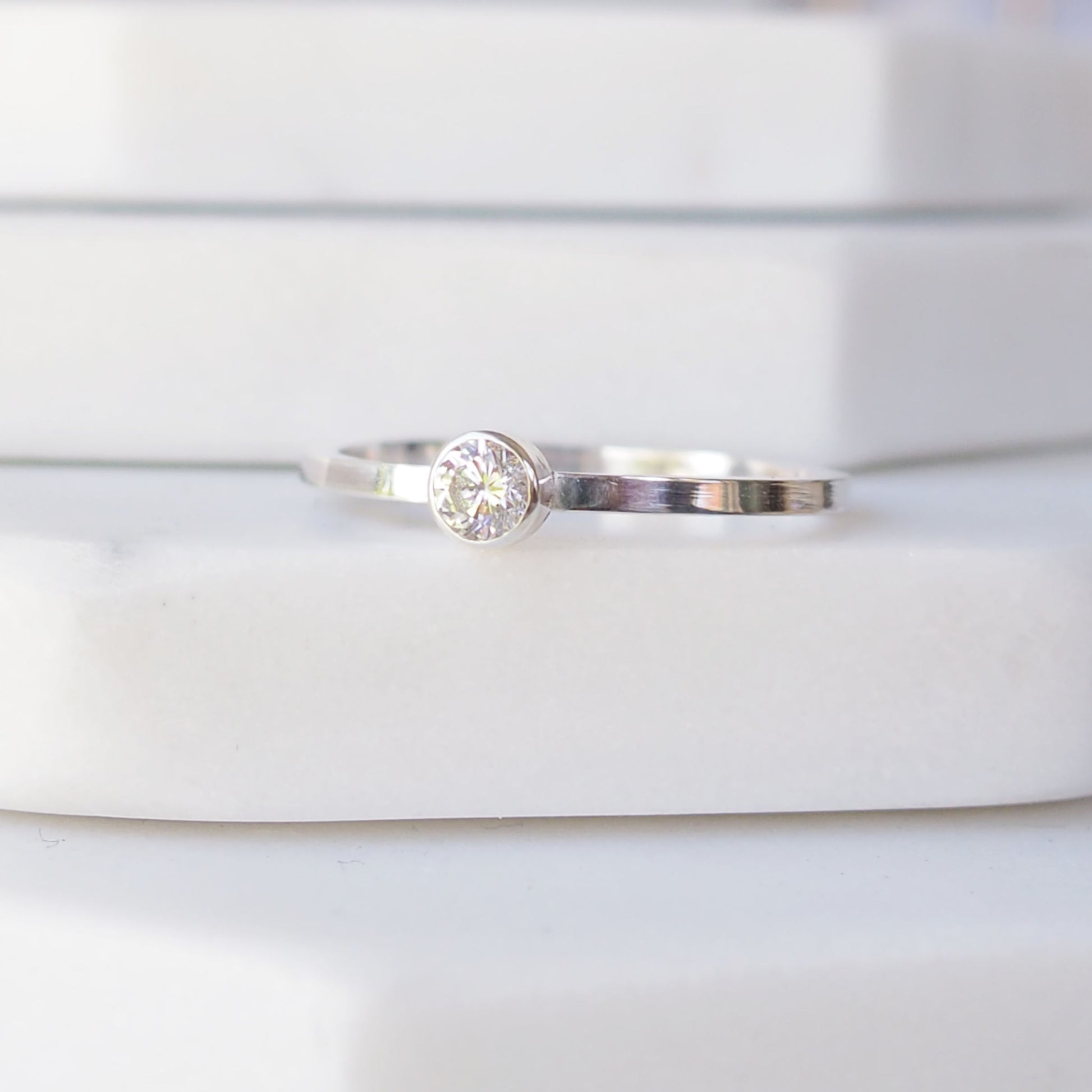 Silver ring with an cubic zirconia gemstone. The ring is simple in style with no embellishment , with a square wire band 1.5mm thick with a simple imitation diamond cubic zirconia 4mm round stone set in an enclosed silver setting. The ring is Sterling Silver and made to your ring size. Handmade in Scotland by Maram Jewellery