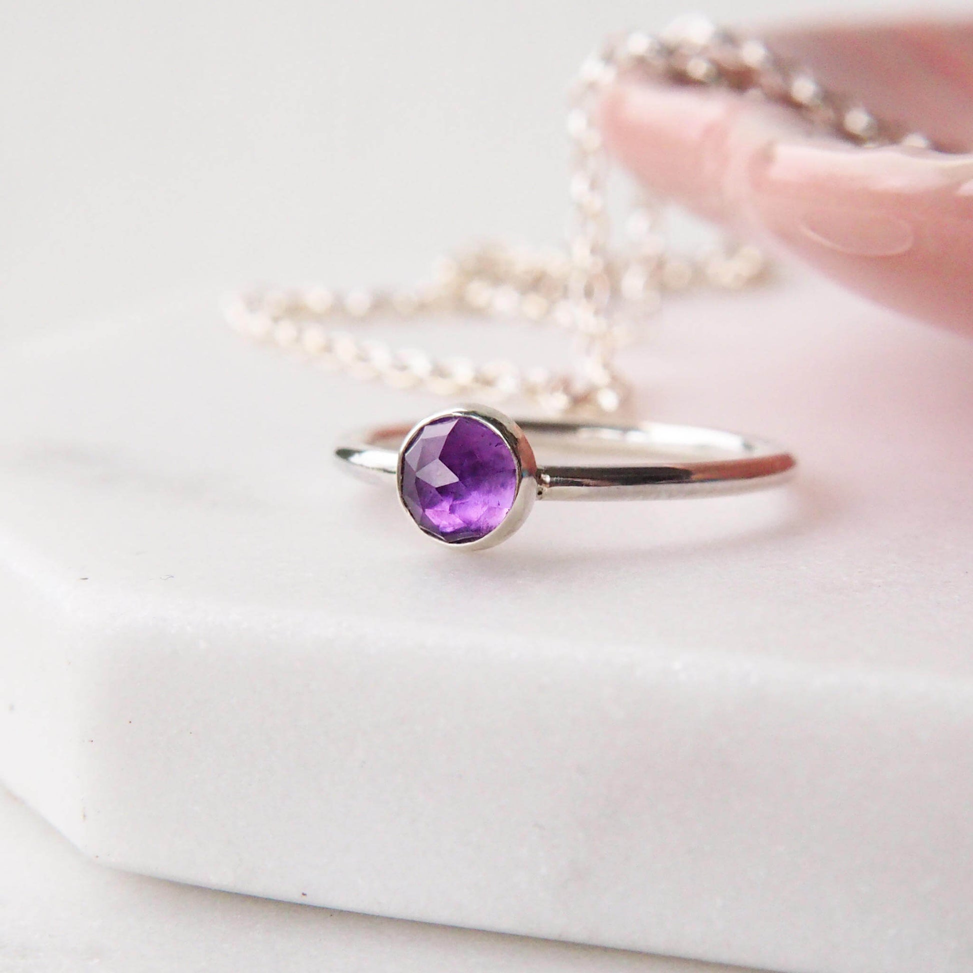 Solitaire sterling silver ring with a round 5mm purple Amethyst. The ring is made in a modern simple style with a 5mm round cabochon set onto a modern halo fully round band. Made to order to your ring size, and handmade in scotland by maram jewellery
