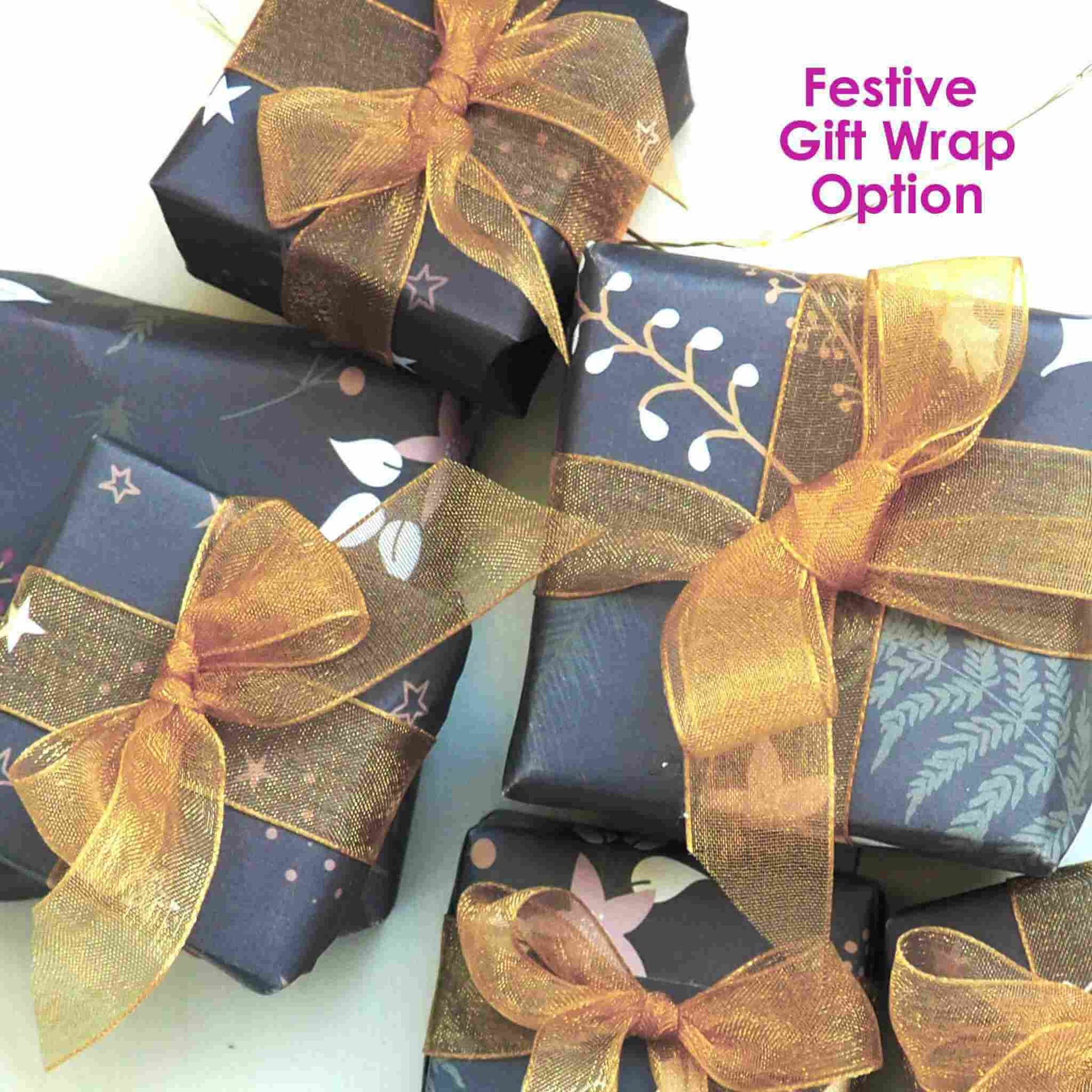 Festive gift wrap for maram jewellery winter gifts with dark green wrap with tiny gold and white star and holly with green fern leaves, all wrapped with gold organza ribbon